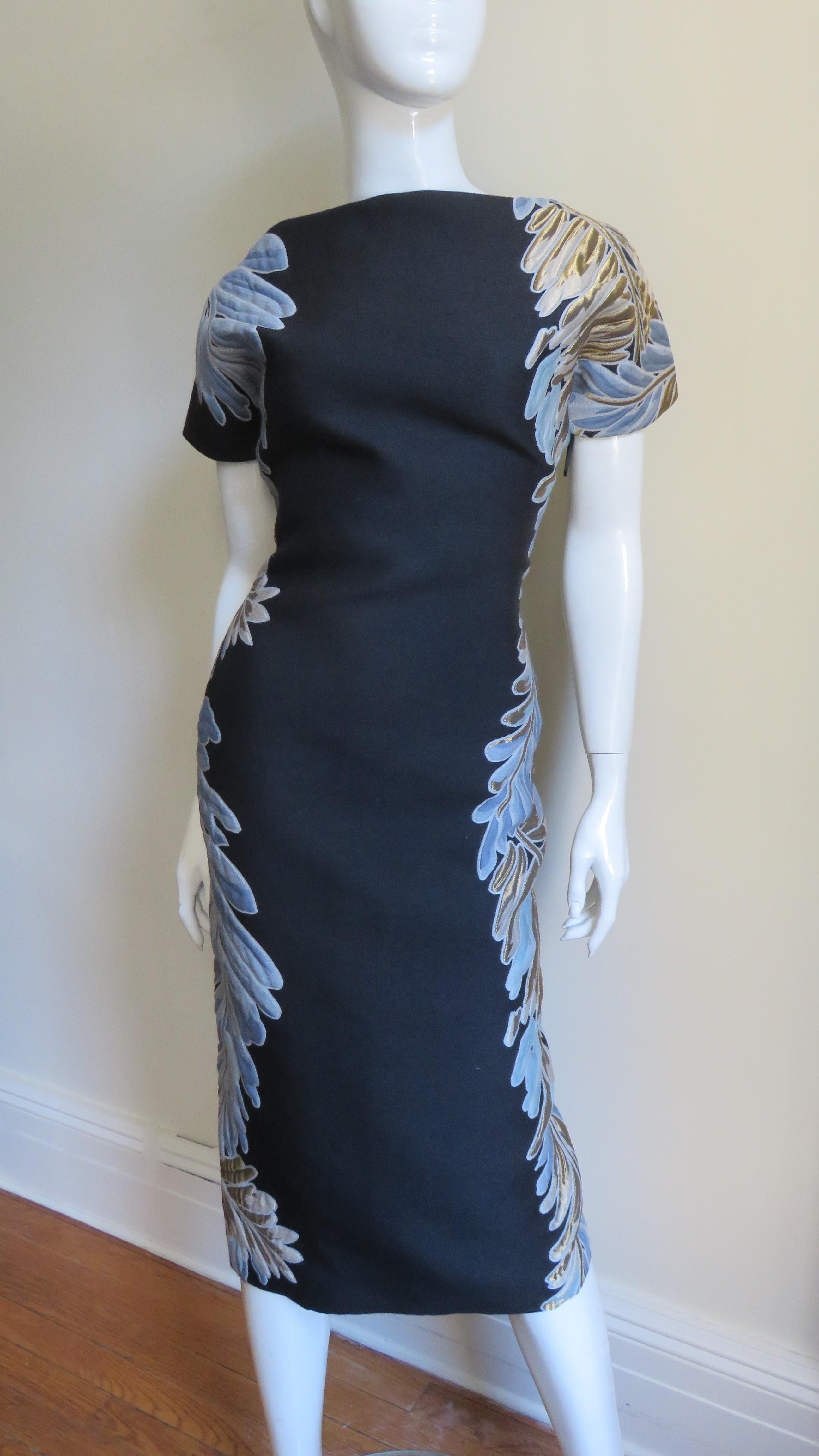 An incredible black silk brocade dress with a blue, beige and gold petal pattern trim strategically and flatteringly placed along the sides and sleeves from Gucci.  It is semi fitted with short sleeves and a fabulous low cut to the waist back. 