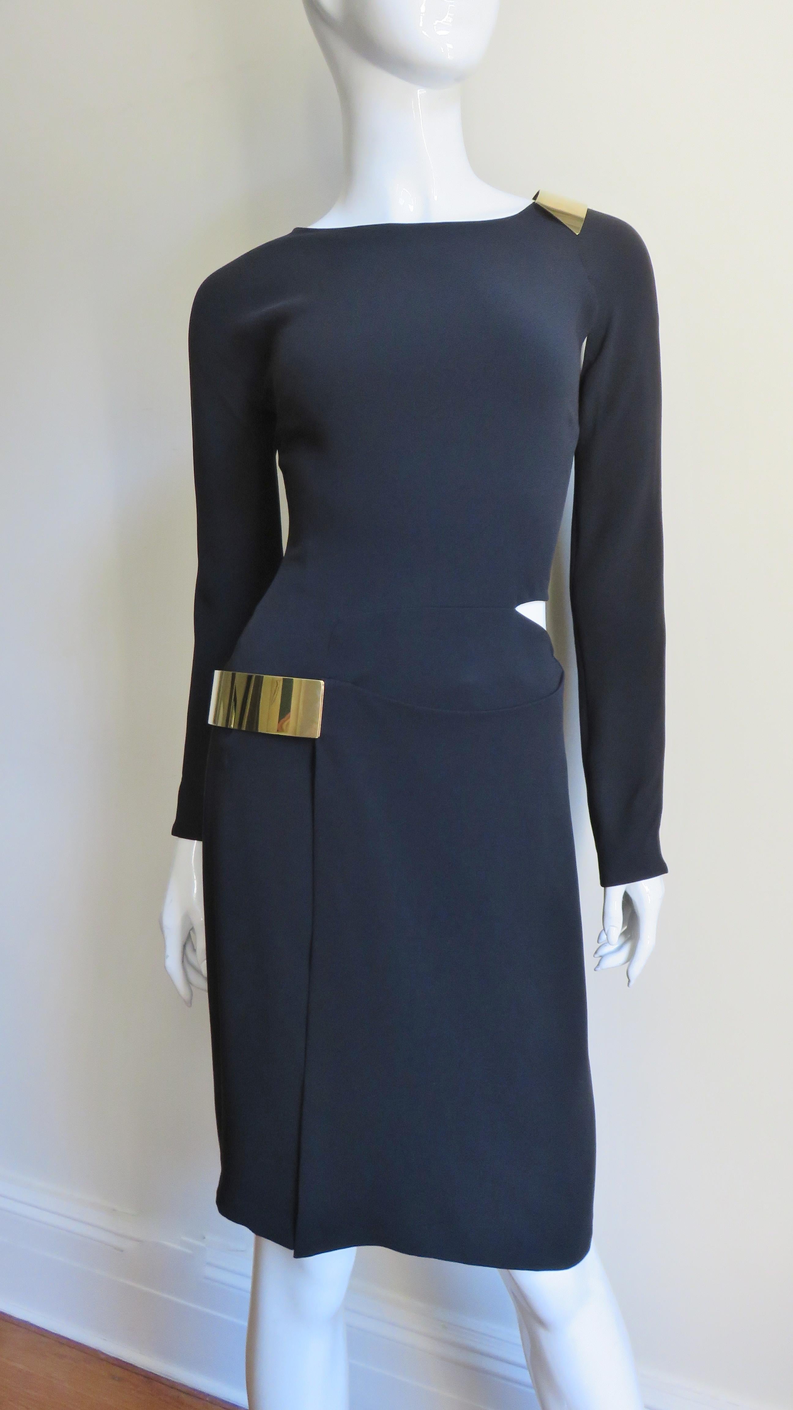 A fabulous black silk jersey dress from Gucci. It has a simple neckline, long zipper cuff sleeves and cut outs at a shoulder and side waist plus a front slit in the straight skirt. The skirt slit and shoulder cut out are highlighted with gold metal