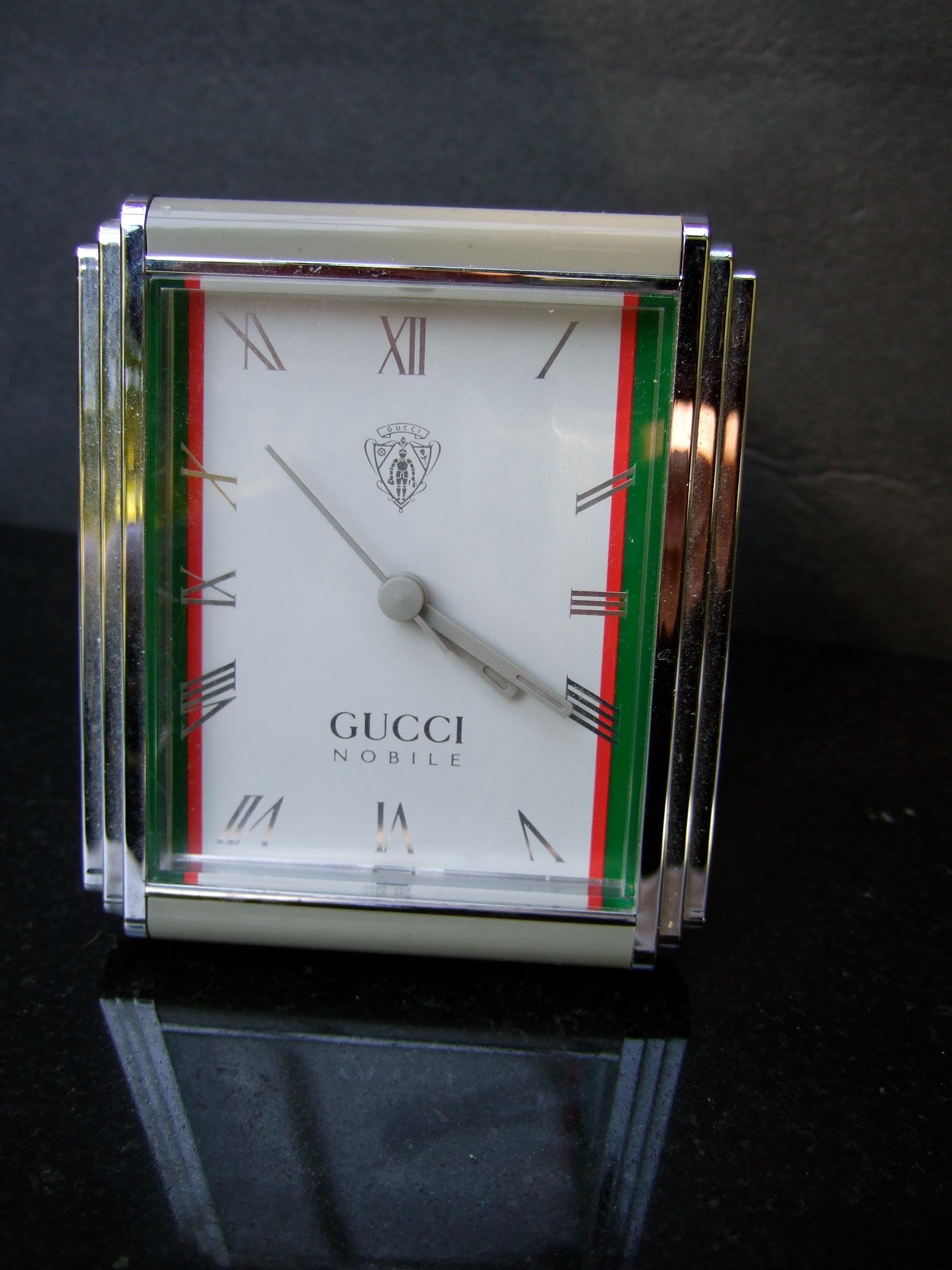 Gucci Nobile silver metallic plastic resin framed battery operated table clock c 1980s
The small table clock is placed in an art deco inspired silver metallic molded
plastic frame that emulates metal. The dial is framed with red & green enamel