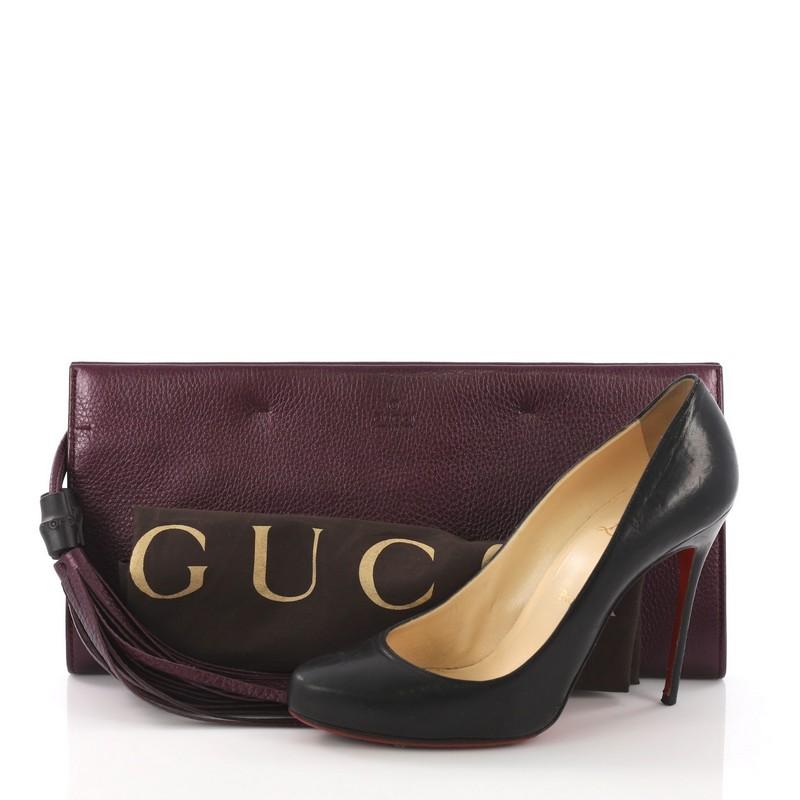 This Gucci Nouveau Clutch with Tassels Leather Large, crafted from purple leather, features double tassel with bamboo details and aged gold-tone hardware. Its hidden magnetic snap closure opens to a purple leather interior with zip pockets. **Note: