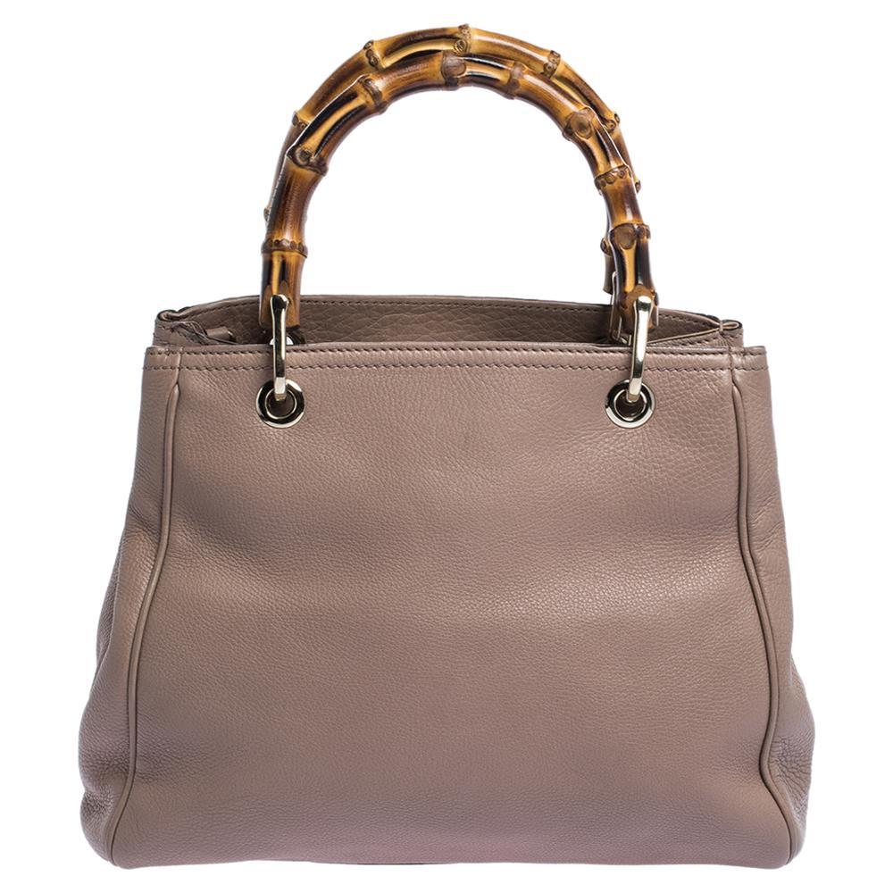 Crafted from nude leather, this stunning Gucci number is held by two wonderfully-created bamboo handles that elevate the whole look. The canvas-lined interior is spacious and will hold all your essentials comfortably. It is finished with gold-tone