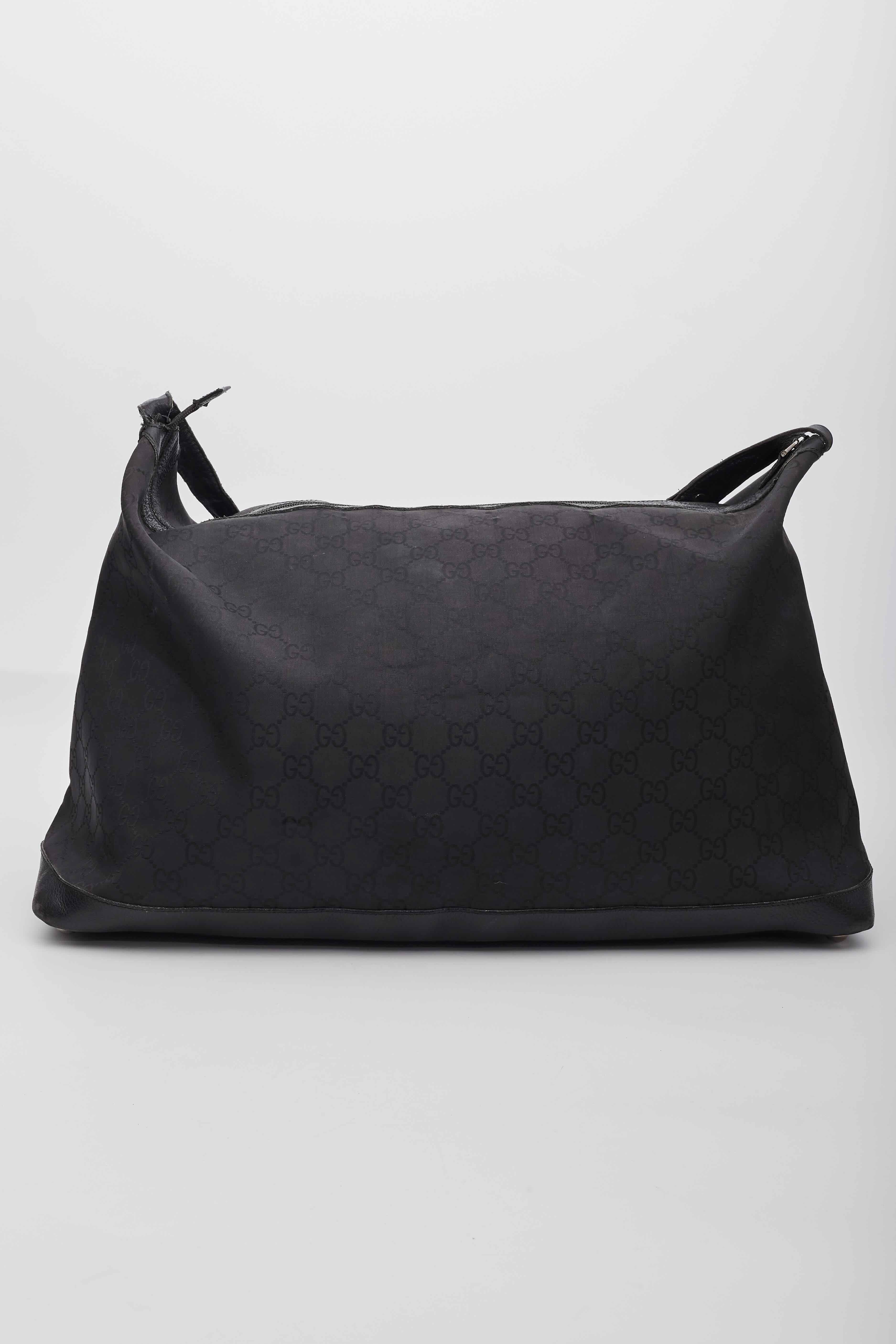 Diese Reisetasche ist aus schwarzem Gucci GG Monogram Canvas gefertigt. Die Tasche verfügt über einen Lederriemen mit polierten silbernen Gliedern und einer verstellbaren Schnalle mit Lederbesatz rund um die Tasche für Struktur und Stärke. Der