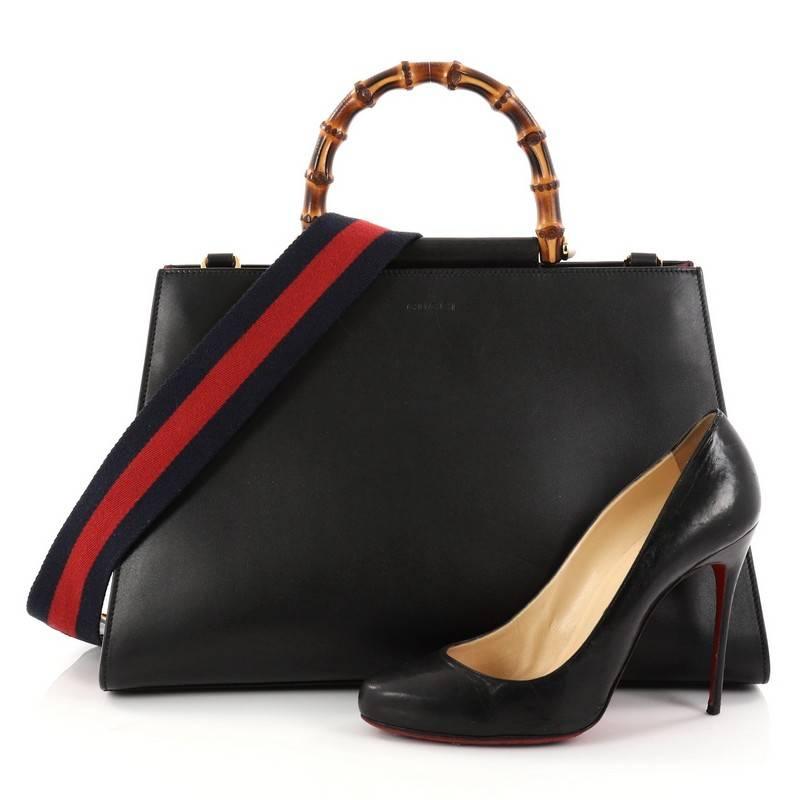 This authentic Gucci Nymphaea Top Handle Bag Leather Medium from 2017 is a stylish bag perfect for the modern fashionista. Crafted in black leather, this gorgeous bag features blue and red nylon Web shoulder strap, bamboo handle with pearls, and