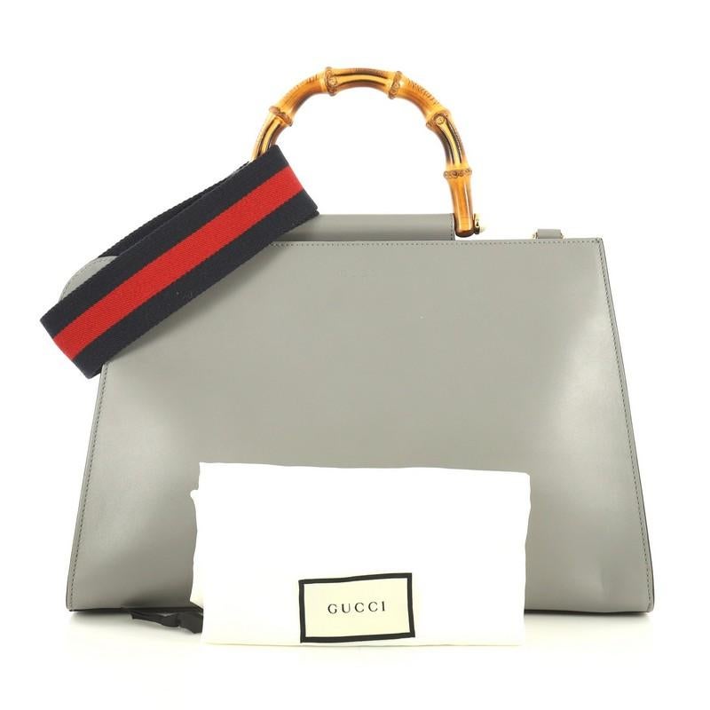 This Gucci Nymphaea Top Handle Bag Leather Medium, crafted in white and gray leather, features bamboo top handle with pearls and gold-tone hardware. Its magnetic snap closure opens to a neutral microfiber interior. 

Estimated Retail Price: