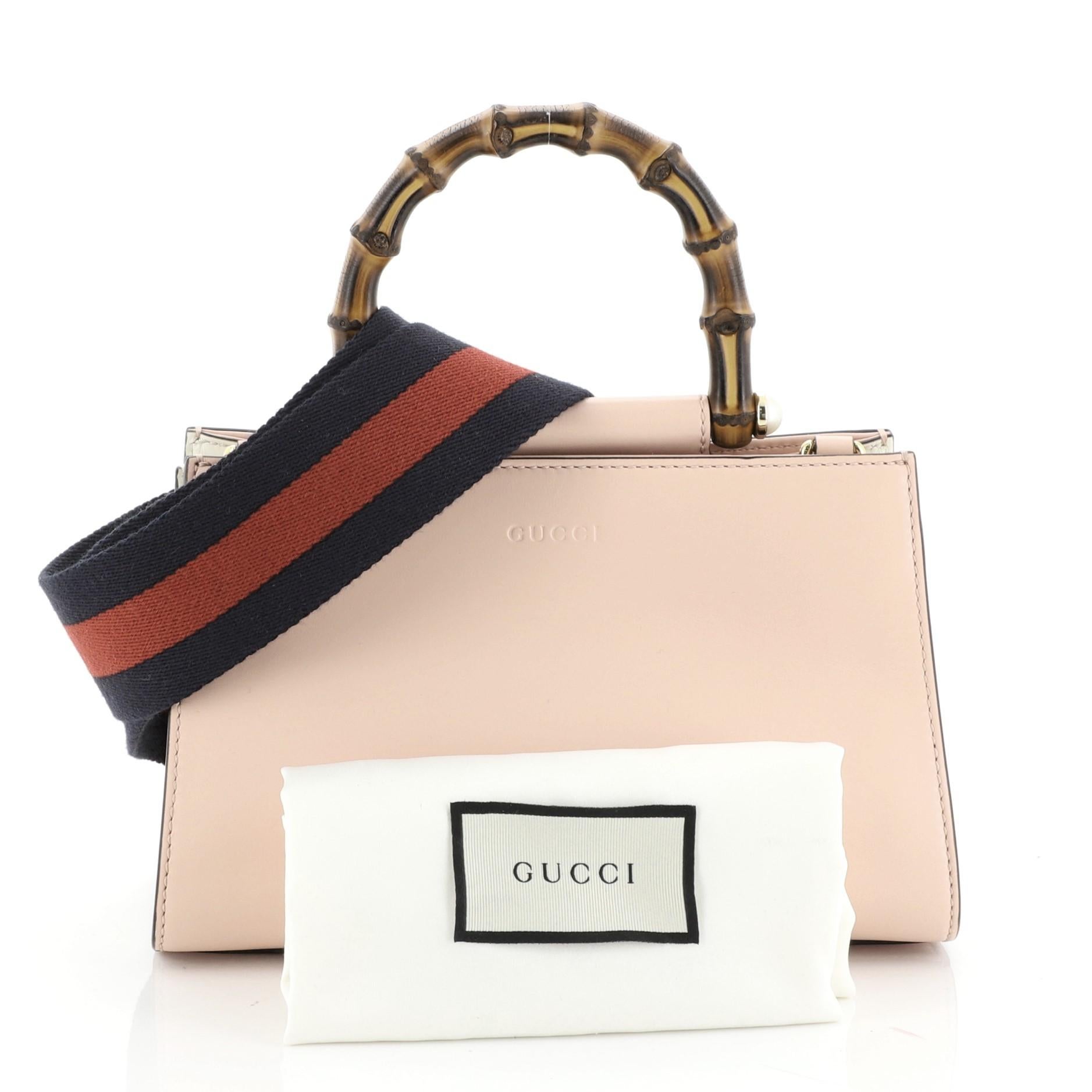 This Gucci Nymphaea Top Handle Bag Leather Mini, crafted in pink leather, features a bamboo handle with pearls and gold-tone hardware. Its magnetic snap closure opens to a gray microfiber interior with zip and slip pockets. These are professional