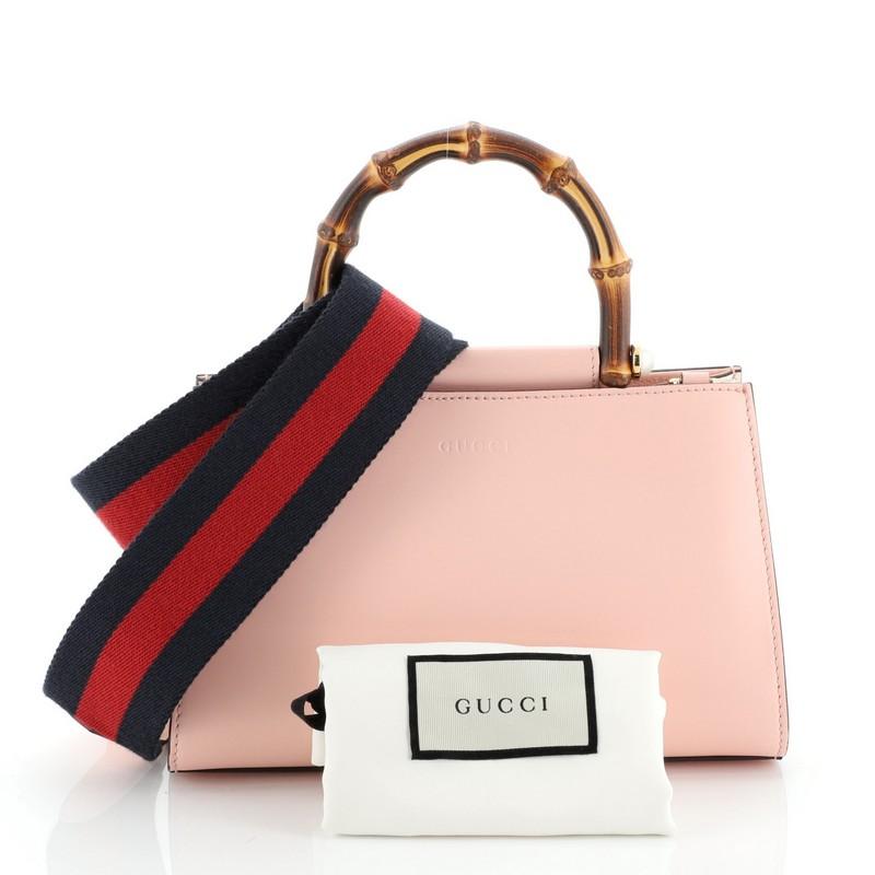 This Gucci Nymphaea Top Handle Bag Leather Mini, crafted in pink leather, features bamboo top handle with pearls and gold-tone hardware. Its magnetic snap closure opens to a gray microfiber interior with zip pocket. 

Estimated Retail Price: