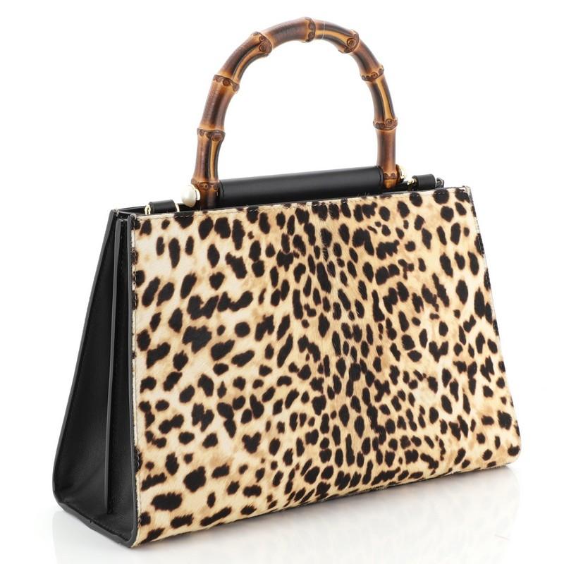 This Gucci Nymphaea Top Handle Bag Printed Calf Hair Small, crafted in brown printed calf hair, features a bamboo top handle and gold-tone hardware. Its magnetic snap closure opens to a neutral microfiber interior with zip and slip pockets.