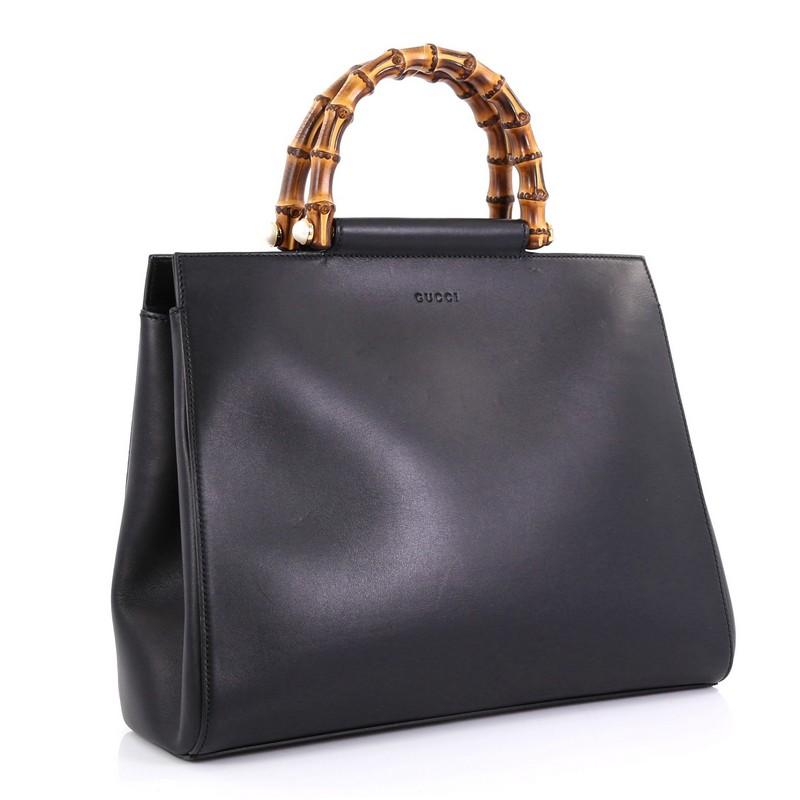 This Gucci Nymphaea Tote Leather Medium, crafted in black leather, features bamboo handles with pearls and gold-tone hardware. It opens to a pale pink microfiber interior with zip and slip pockets. **Note: 

Estimated Retail Price: $2,390
Condition: