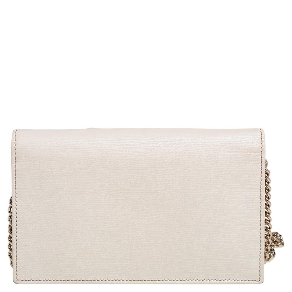 Sling on this Gucci WOC for a classy finish. This gorgeous wallet is crafted from off-white leather with a gold-tone Gucci logo on the flap corner and a matching chain. The front flap opens to a leather and fabric-lined interior with a zipper pocket
