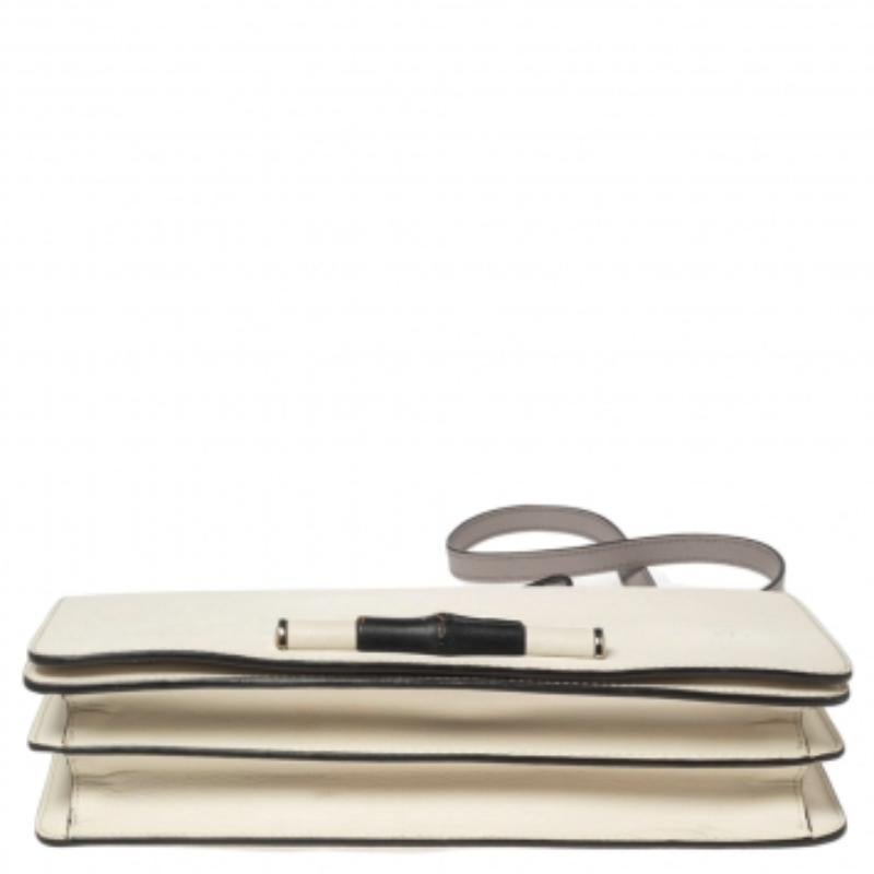 Confectionné en cuir blanc cassé, ce fabuleux sac Gucci est doté d'un rabat frontal orné du motif bambou emblématique de la marque. Une lanière en cuir et deux compartiments intérieurs complètent ce sac Lady Bamboo.