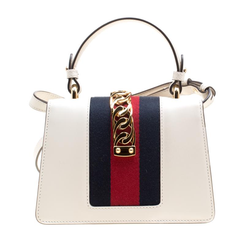 From the house of Gucci comes this gorgeous Sylvie bag that will perfectly complement all your outfits. It has been luxuriously crafted from off-white leather and styled with a chain-web decorated flap and a buckle lock to secure the suede interior.