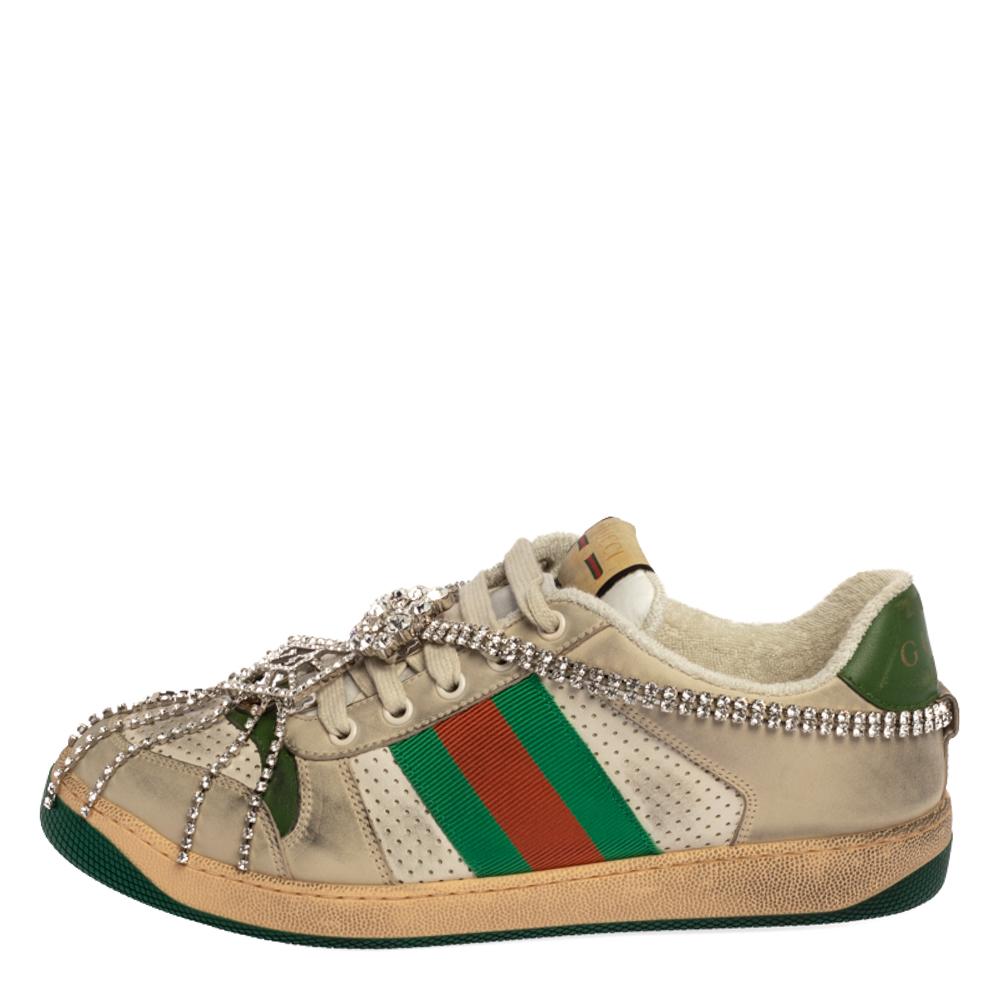 This pair of Screener sneakers by Gucci has been treated for a vintage, distressed effect. They are crafted from leather and feature the famous Web trim, the iconic GG logo, and lace-up vamps adorned with crystals. The low-top shoe is made in