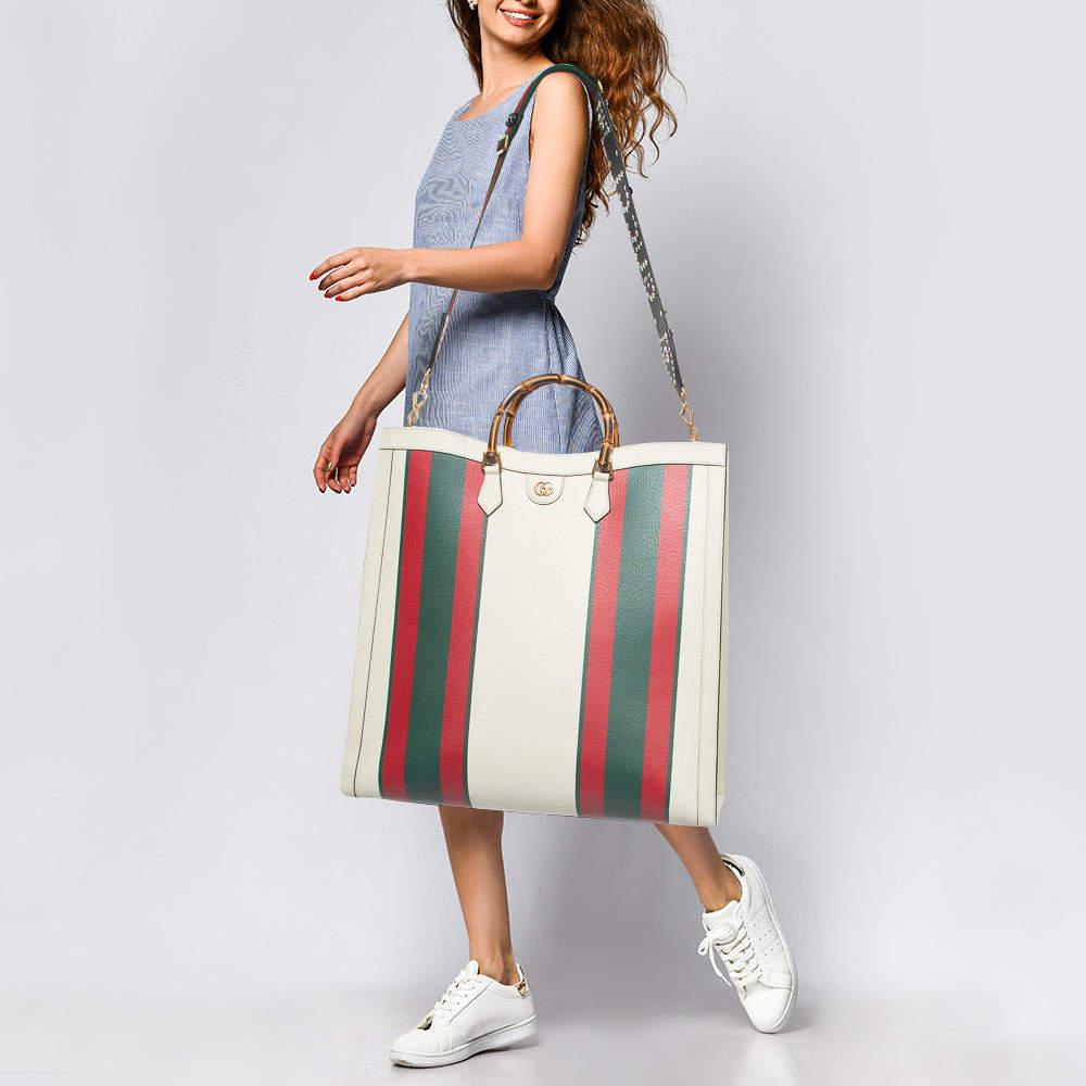 The Gucci Diana Tote exudes sophistication with its luxurious off-white leather adorned with the iconic green and red web print. This maxi-sized tote combines timeless elegance and modern style, making it a statement piece for any fashion-forward