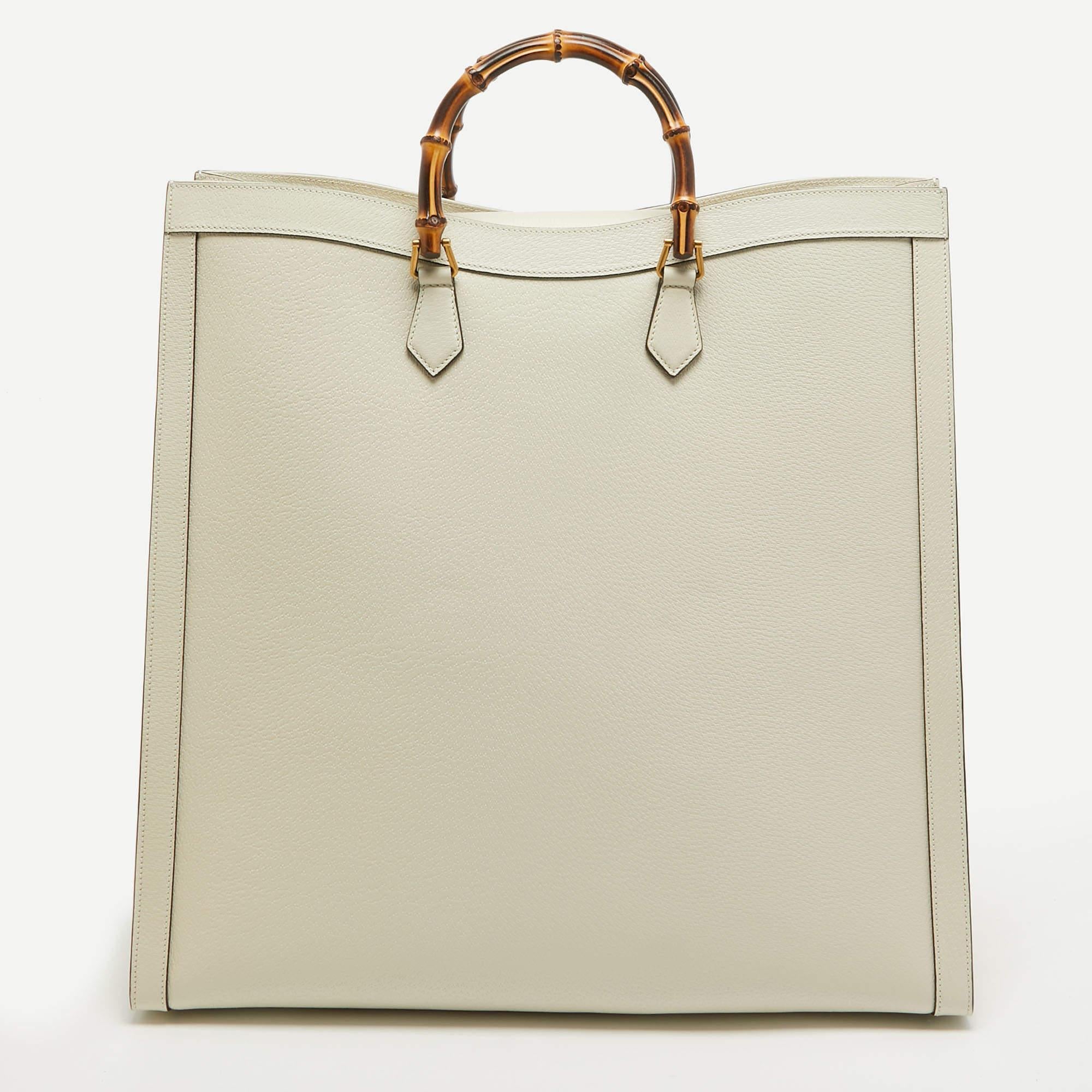 The Gucci Diana Tote exudes sophistication with its luxurious off-white leather adorned with the iconic green and red web print. This maxi-sized tote combines timeless elegance and modern style, making it a statement piece for any fashion-forward