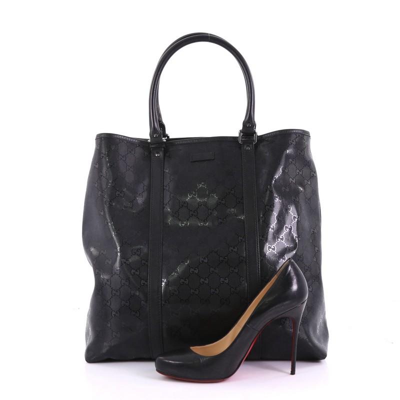 This Gucci Open Tote GG Imprime Large, crafted in black GG imprime, features dual rolled handles and gunmetal-tone hardware. Its magnetic closure opens to a black fabric interior with zip pockets. **Note: Shoe photographed is used as a sizing