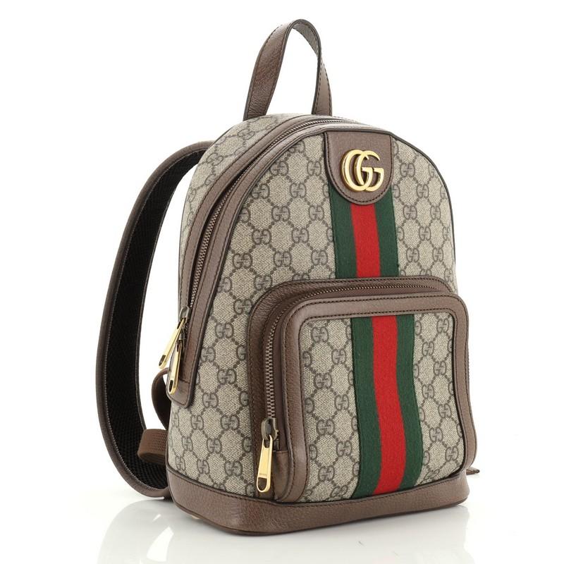 This Gucci Ophidia Backpack GG Coated Canvas Small, crafted in brown GG coated canvas, features dual shoulder straps, web strap detailing, exterior zip pocket and aged gold-tone hardware. Its zip closure opens to a neutral fabric interior.