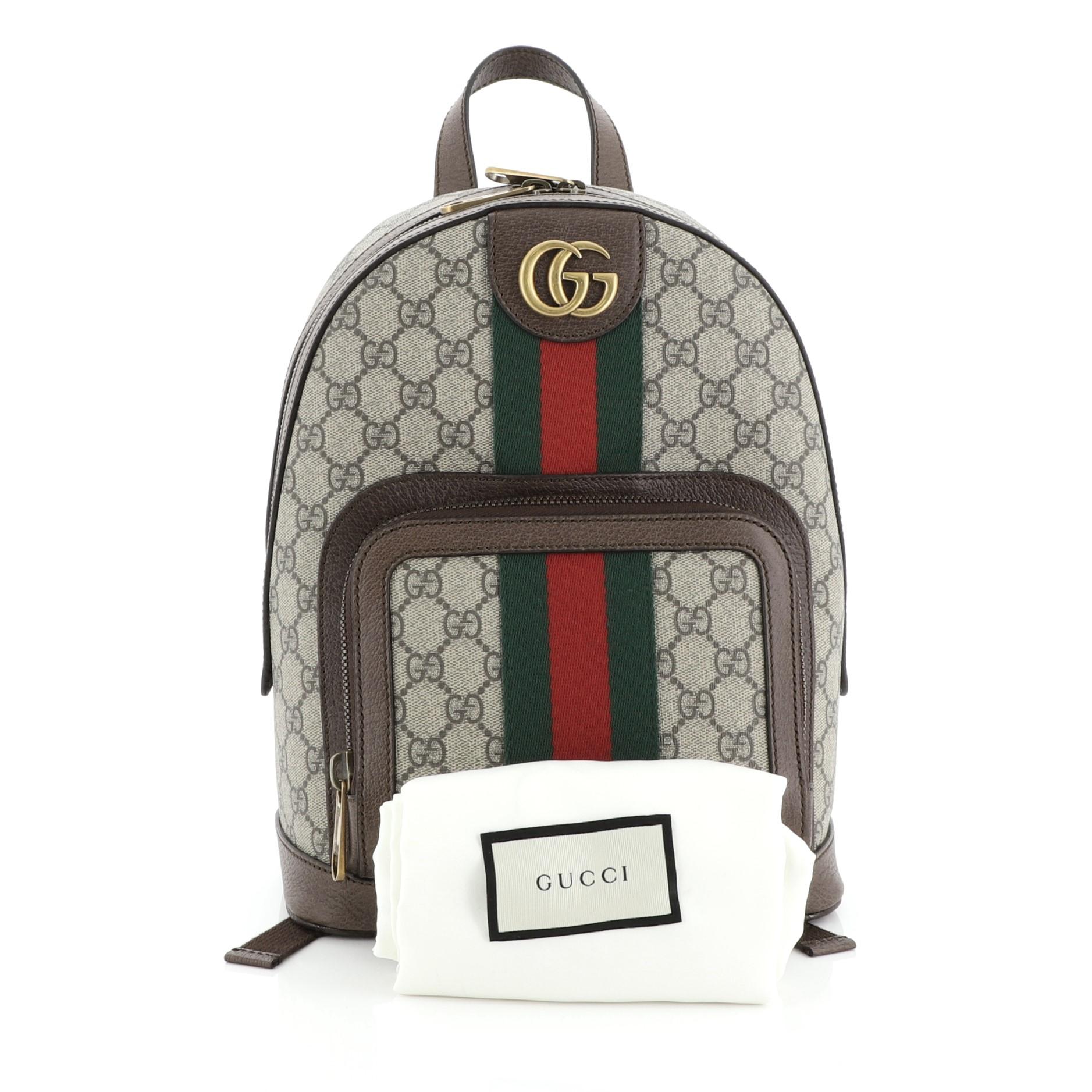 This Gucci Ophidia Backpack GG Coated Canvas Small, crafted in brown GG coated canvas, features dual shoulder straps, web strap detailing, exterior zip pocket and aged gold-tone hardware. Its zip closure opens to a neutral canvas interior.