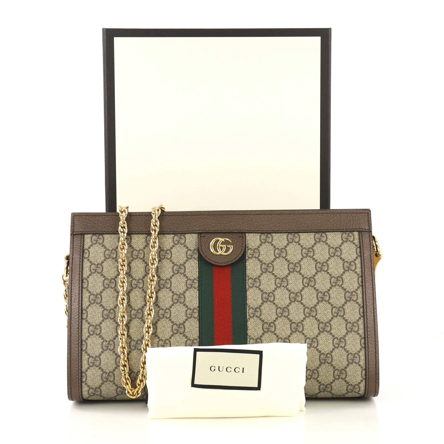 This Gucci Ophidia Chain Shoulder Bag GG Coated Canvas Medium, crafted in brown GG coated canvas, features inlaid web stripe detail, chain link shoulder strap, and gold-tone hardware. Its hidden magnetic snap closure opens to a blue satin interior