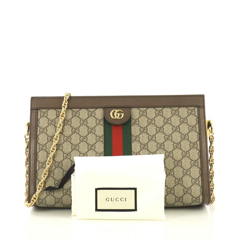 This Gucci Ophidia Chain Shoulder Bag GG Coated Canvas Medium, crafted in brown GG coated canvas, features inlaid web stripe detail, chain link shoulder strap, and gold-tone hardware. Its hidden magnetic snaps closure opens to a blue satin interior