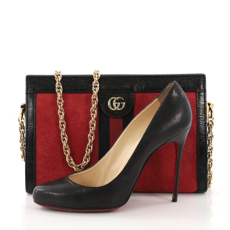 This Gucci Ophidia Chain Shoulder Bag Suede Small, crafted in red suede and black leather, features a web stripe detail, chain link shoulder strap, leather trim, Gucci logo, and gold-tone hardware. Its hidden magnetic snaps closure opens to a blue