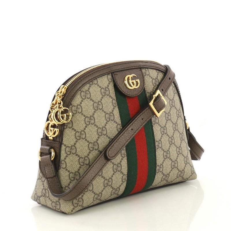 This Gucci Ophidia Dome Shoulder Bag GG Coated Canvas Small, crafted in brown GG coated canvas, features an adjustable leather strap, web striped design, and gold-tone hardware. Its zip closure opens to a blue satin interior with slip pocket.