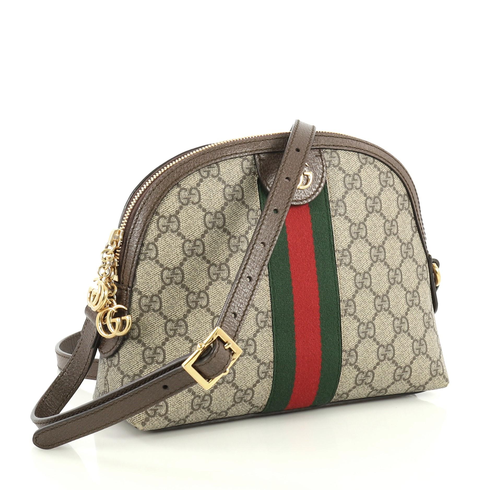This Gucci Ophidia Dome Shoulder Bag GG Coated Canvas Small, crafted in brown GG coated canvas, features an adjustable leather strap, web striped design, and gold-tone hardware. Its zip closure opens to a blue satin interior with slip pockets.