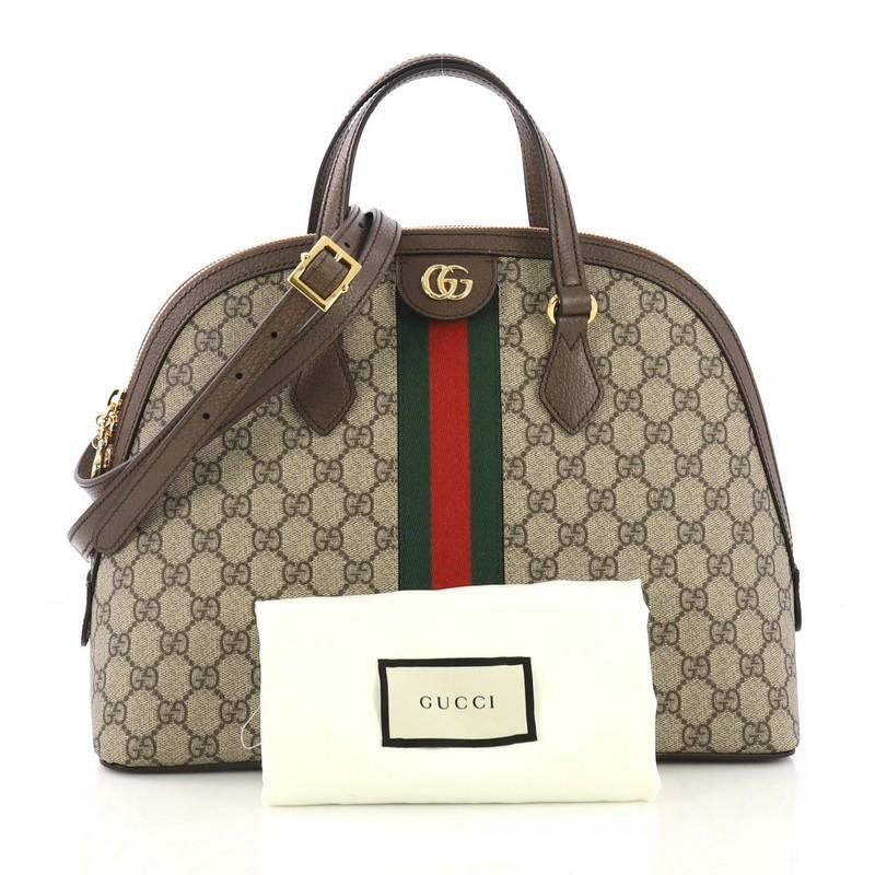 This Gucci Ophidia Dome Top Handle Bag GG Coated Canvas Medium, crafted in light brown GG canvas, features dual top handles, inlaid web stripe detail, and gold-tone hardware. Its zip closure opens to a beige microfiber interior with side zip and