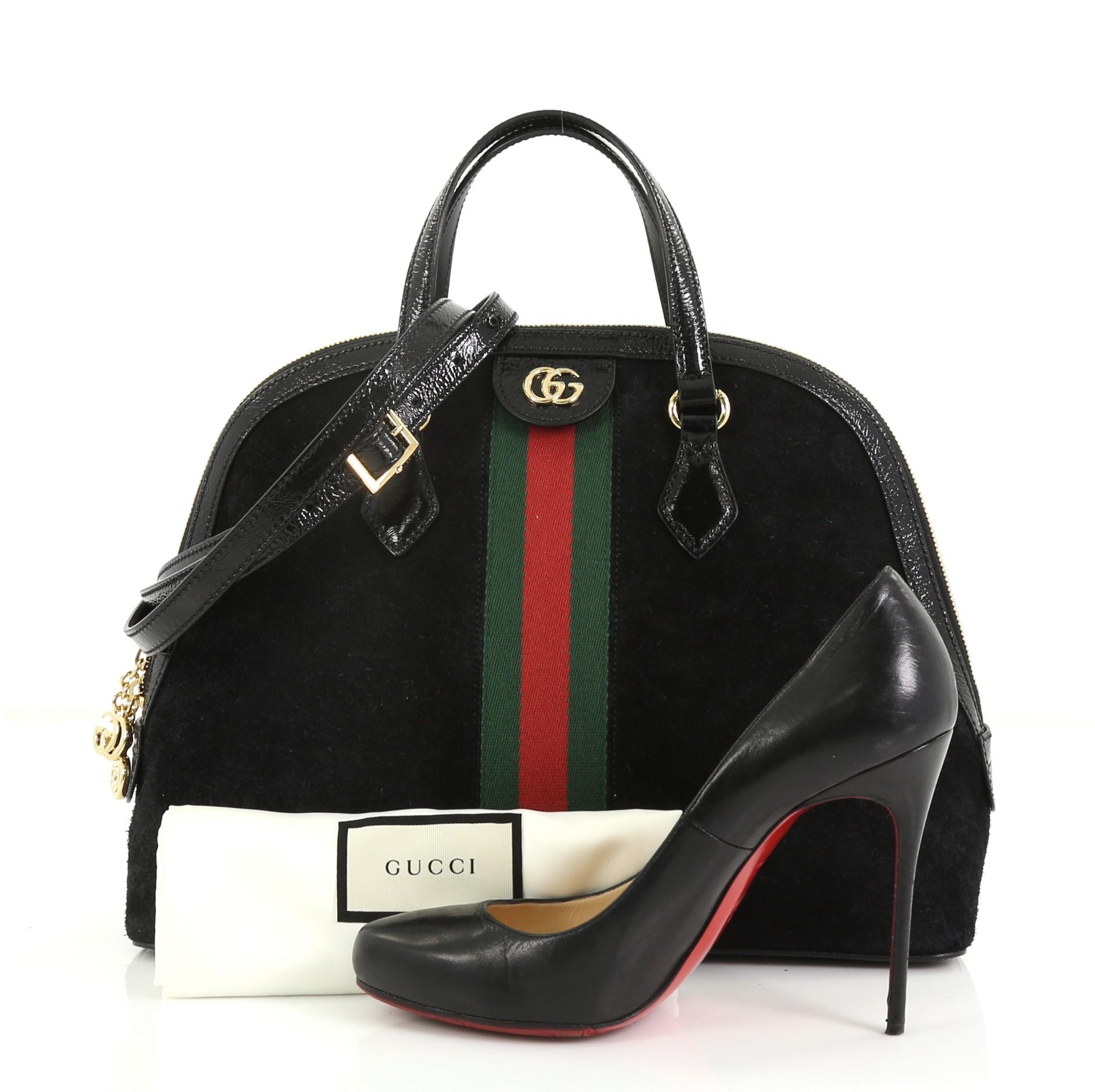 This Gucci Ophidia Dome Top Handle Bag Suede Medium, crafted in black suede, features inlaid web stripe detail, dual leather top handles, and gold-tone hardware. Its zip closure opens to a beige microfiber interior with side slip pockets.