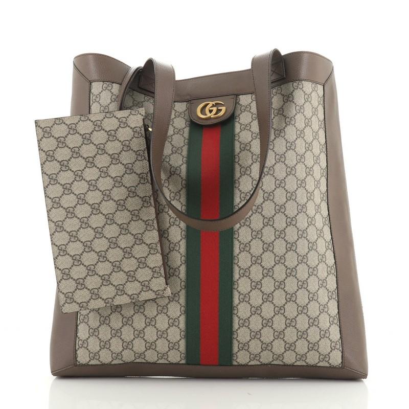 This Gucci Ophidia Soft Open Tote GG Coated Canvas Large, crafted in brown GG coated canvas, features dual leather shoulder straps, Gucci web detail, and aged gold-tone hardware. It opens to a neutral microfiber interior. 

Estimated Retail Price: