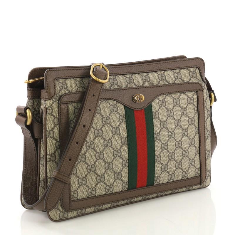 This Gucci Ophidia Zip Shoulder Bag GG Coated Canvas Medium, crafted in light brown GG coated canvas, features an adjustable leather strap, web striped design, exterior front pocket, and aged gold-tone hardware. Its zip closure opens to a beige