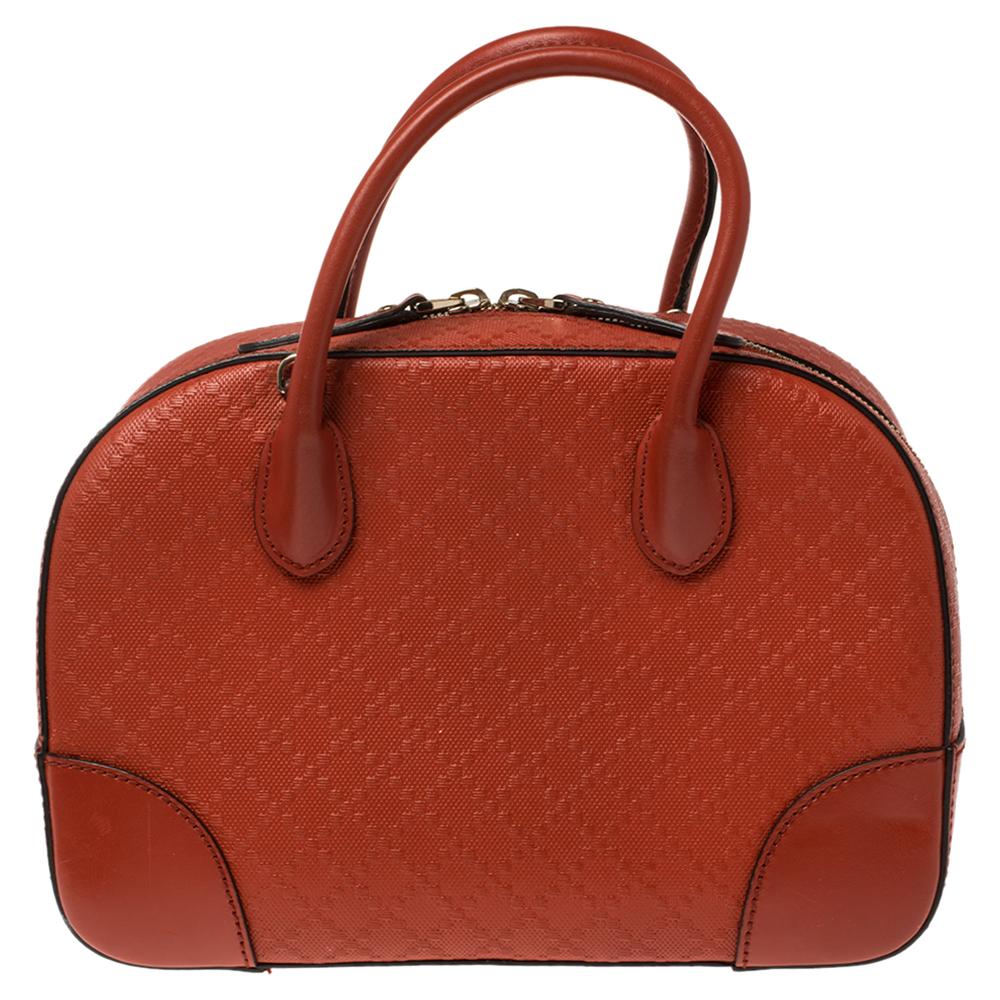 This Gucci satchel is crafted from bright orange Diamante leather with smooth trims into a structured silhouette. The bag features dual handles and protective metal feet at the bottom. The top zip closure opens to a fabric-lined interior that houses