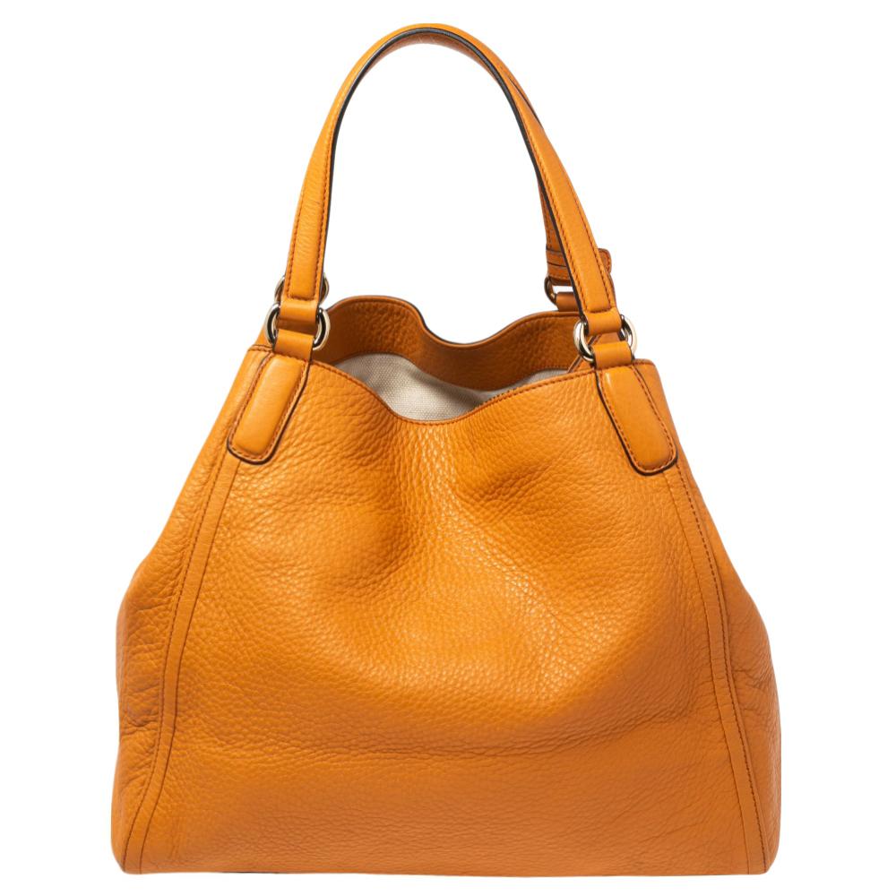 This Gucci Soho shoulder bag is practical yet chic. The bag is crafted using textured leather and wears the signature GG logo on the front. It is a beautiful shade of orange with a spacious canvas interior for your essentials, two handles, and a