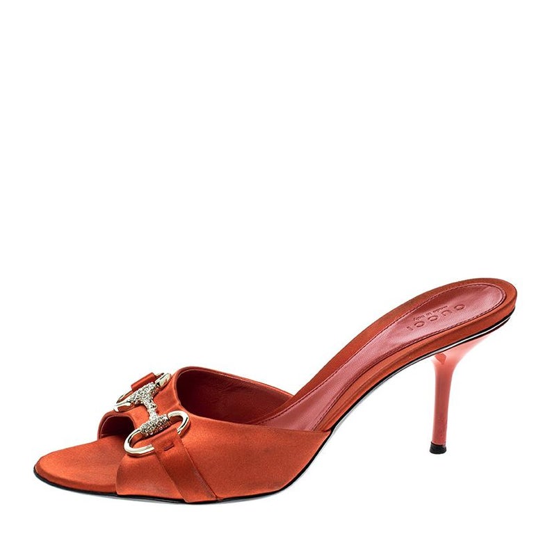 Finesse and poise will all come naturally to you when you step out in this pair of Horsebit slides from Gucci. Crafted from orange satin, the slides have been styled with Horsebit details embedded with crystals and 8.5 cm heels. The insoles have