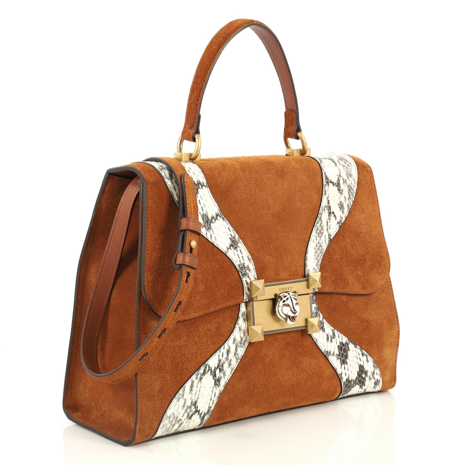 This Gucci Osiride Top Handle Bag Suede with Snakeskin Medium, crafted in brown suede and genuine snakeskin, features a flat top handle, adjusatable shoulder strap, front flap with enameled feline head metal closure and aged gold-tone hardware. It