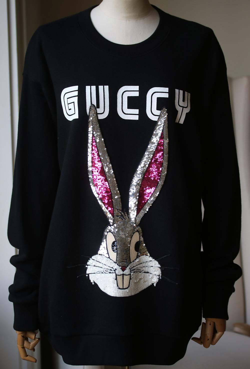 Black cotton sweatshirt from Gucci. Cream and black 'Bugs Bunny' patch with silver-tone, white and pink sequins and printed 'Guccy' lettering at front. Round neck. Long sleeves. Elasticated hem and cuffs. 100% Cotton. 

Size - Medium (UK 10, US 6,