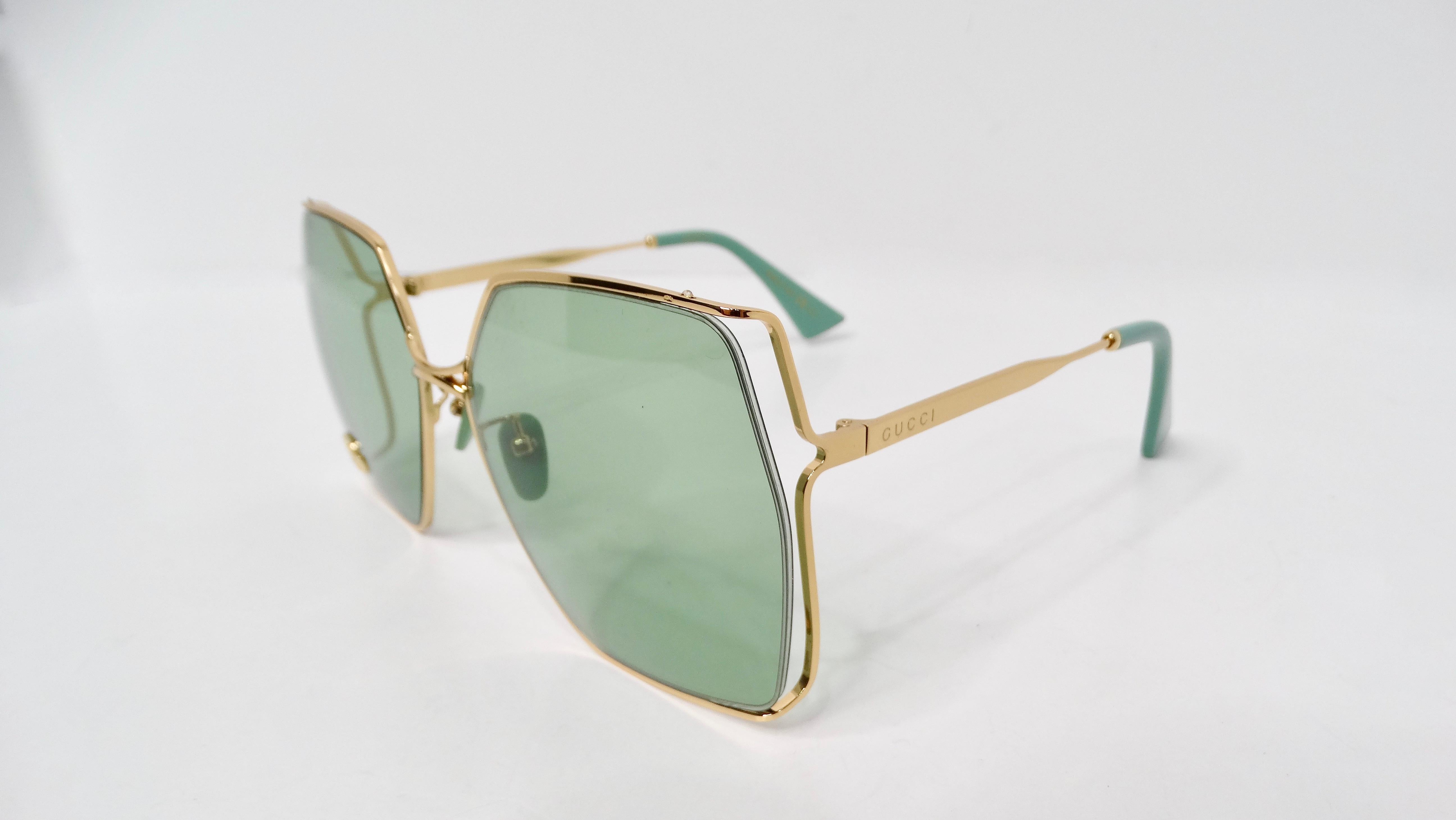 Embrace your bold fashion sense with the Gucci Oversized Green With Gold-Tone Metal Frame GG Logo Sunglasses. These striking accessories showcase a vibrant green frame and stems, beautifully complemented by a luxurious gold-tone metal frame that