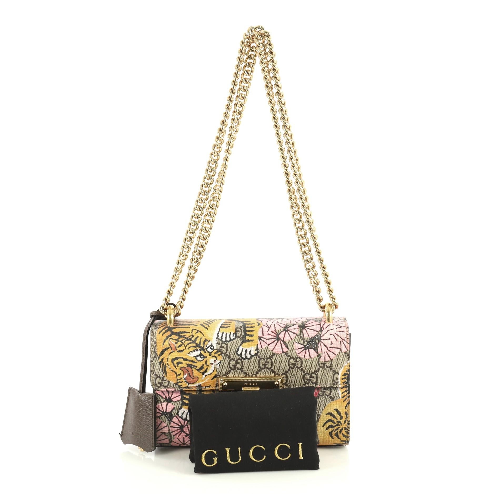 This Gucci Padlock Shoulder Bag Bengal Print GG Coated Canvas Small, crafted in brown GG coated canvas with Bengal print, features chain link strap, exterior back pocket, and gold-tone hardware. Its push-lock closure opens to a neutral microfiber
