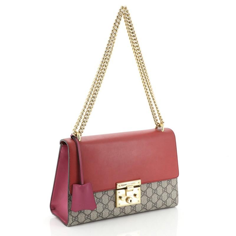 This Gucci Padlock Shoulder Bag GG Coated Canvas and Leather Medium, crafted in brown GG coated canvas and multicolor leather, features chain link strap, exterior back slip pocket, and gold-tone hardware. Its push-lock closure opens to a brown