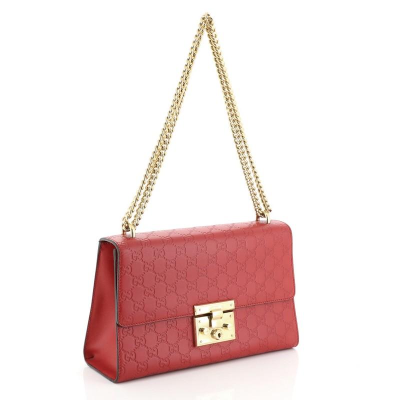 This Gucci Padlock Shoulder Bag Guccissima Leather Medium, crafted in red guccissima leather, features chain link strap, exterior slip pocket, and gold-tone hardware. Its push-lock closure opens to a neutral microfiber interior with side zip and