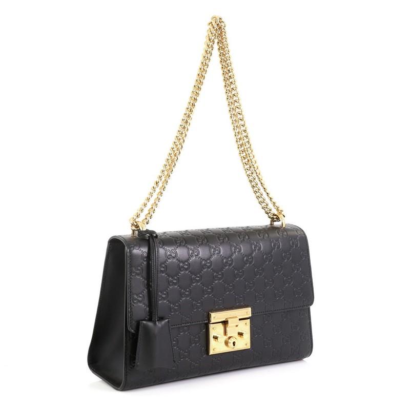 This Gucci Padlock Shoulder Bag Guccissima Leather Medium, crafted in black guccissima leather, features chain link strap, exterior card slip pocket, and gold-tone hardware. Its push-lock closure opens to a neutral microfiber interior with side zip