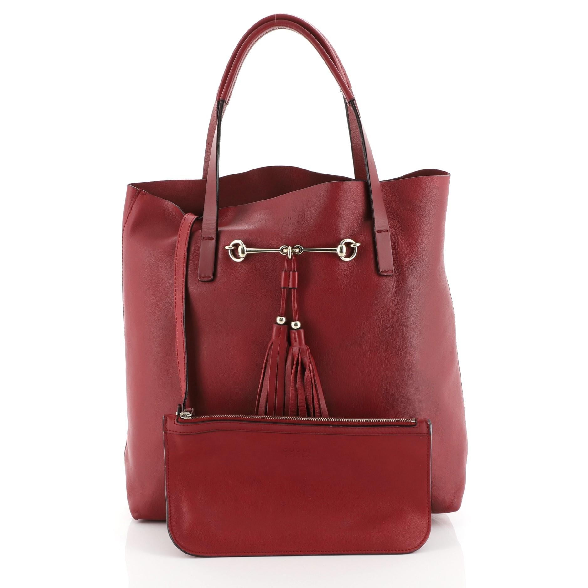 This Gucci Park Avenue Tote Leather Medium, crafted in red leather, features dual flat leather handles, horsebit with fringe leather tassels, and gold-tone hardware. Its wide top opening showcases a red raw leather interior. 

Estimated Retail