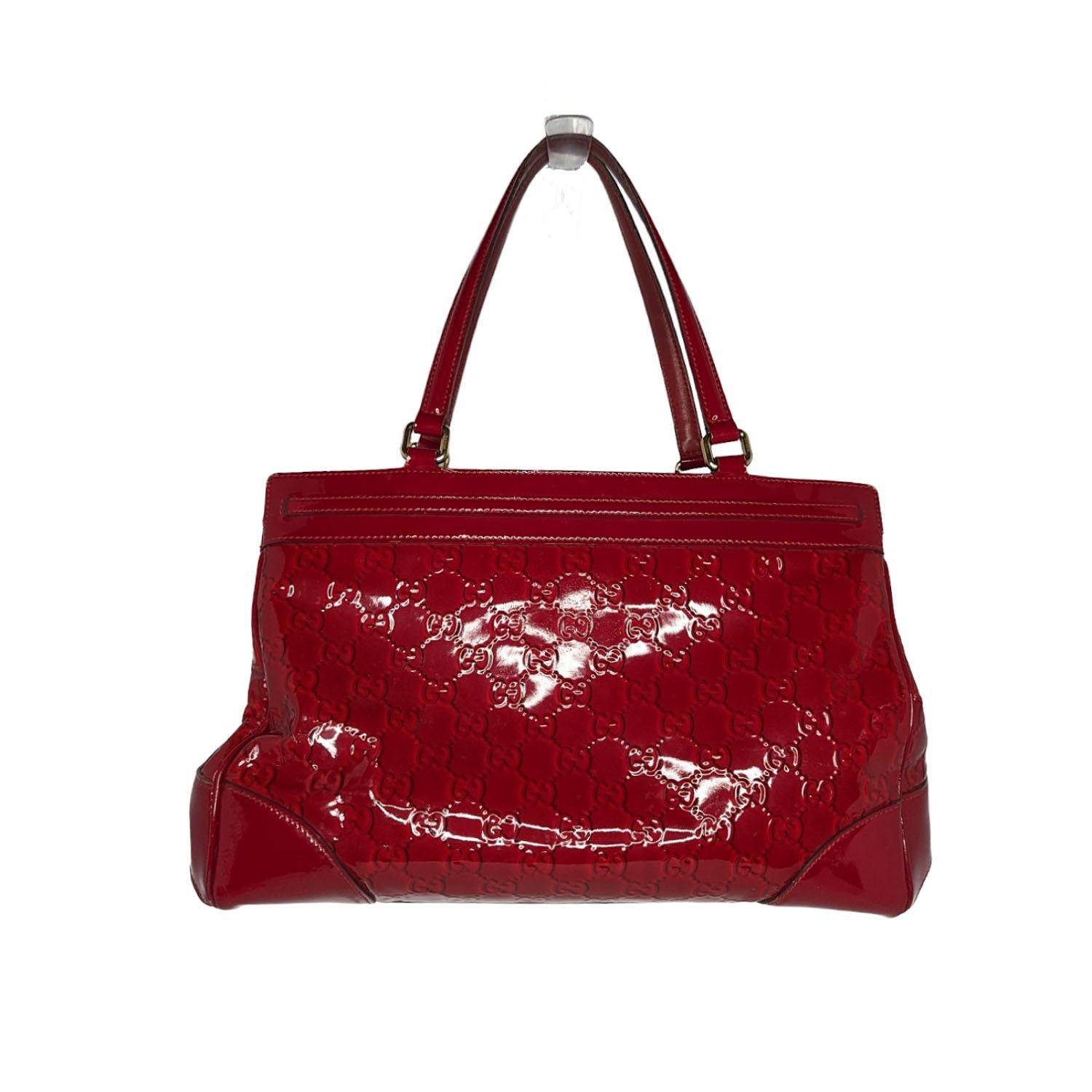 This sophisticated tote is crafted of glossy Guccissima Gucci GG monogram embossed patent leather in bright red. The bag features leather strap top handles with brass links and leather top trim with a leather bow embellishment. The top zipper opens