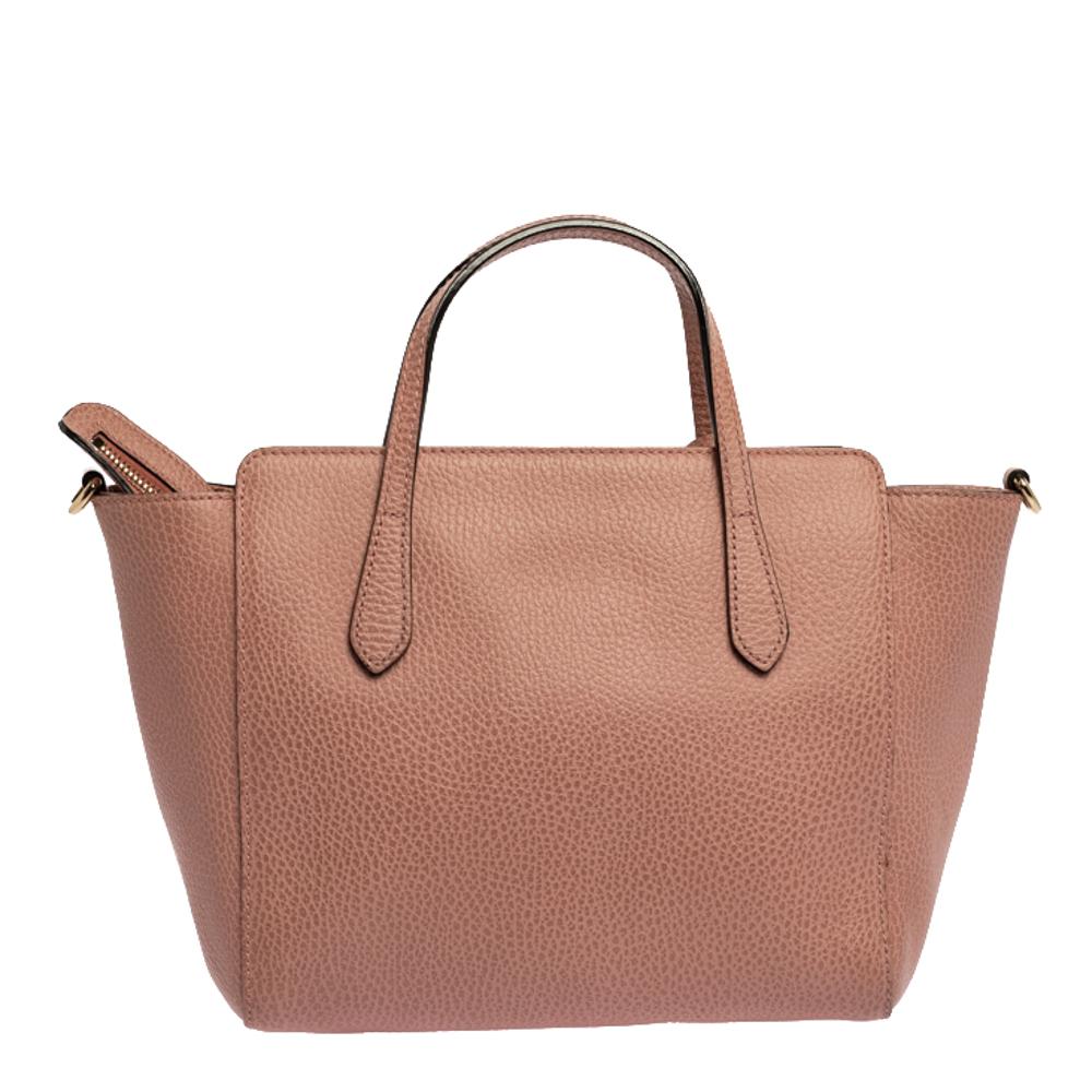 High in appeal and style, this Swing tote is a Gucci creation. It has been crafted from quality leather in Italy and shaped to exude class and luxury. The peach-hued bag comes with two handles, a spacious canvas-lined interior, and the brand label