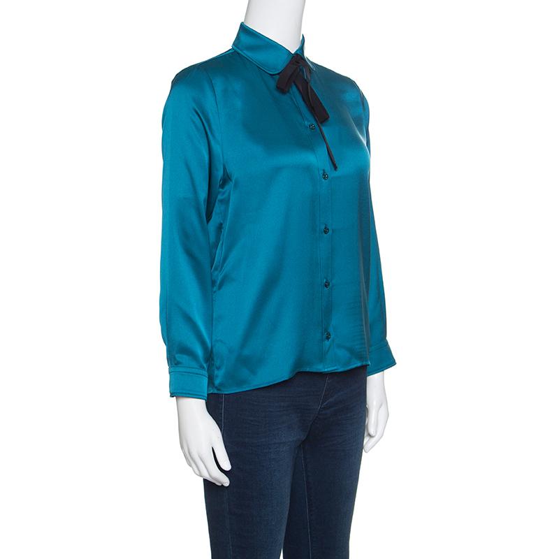 Isn't this shirt from Gucci just wonderful! The peacock blue shirt is made of 100% silk and features a simple structured silhouette. It flaunts collars with a satin ribbon tie detailing, front button fastenings and long sleeves. Pair it with denims