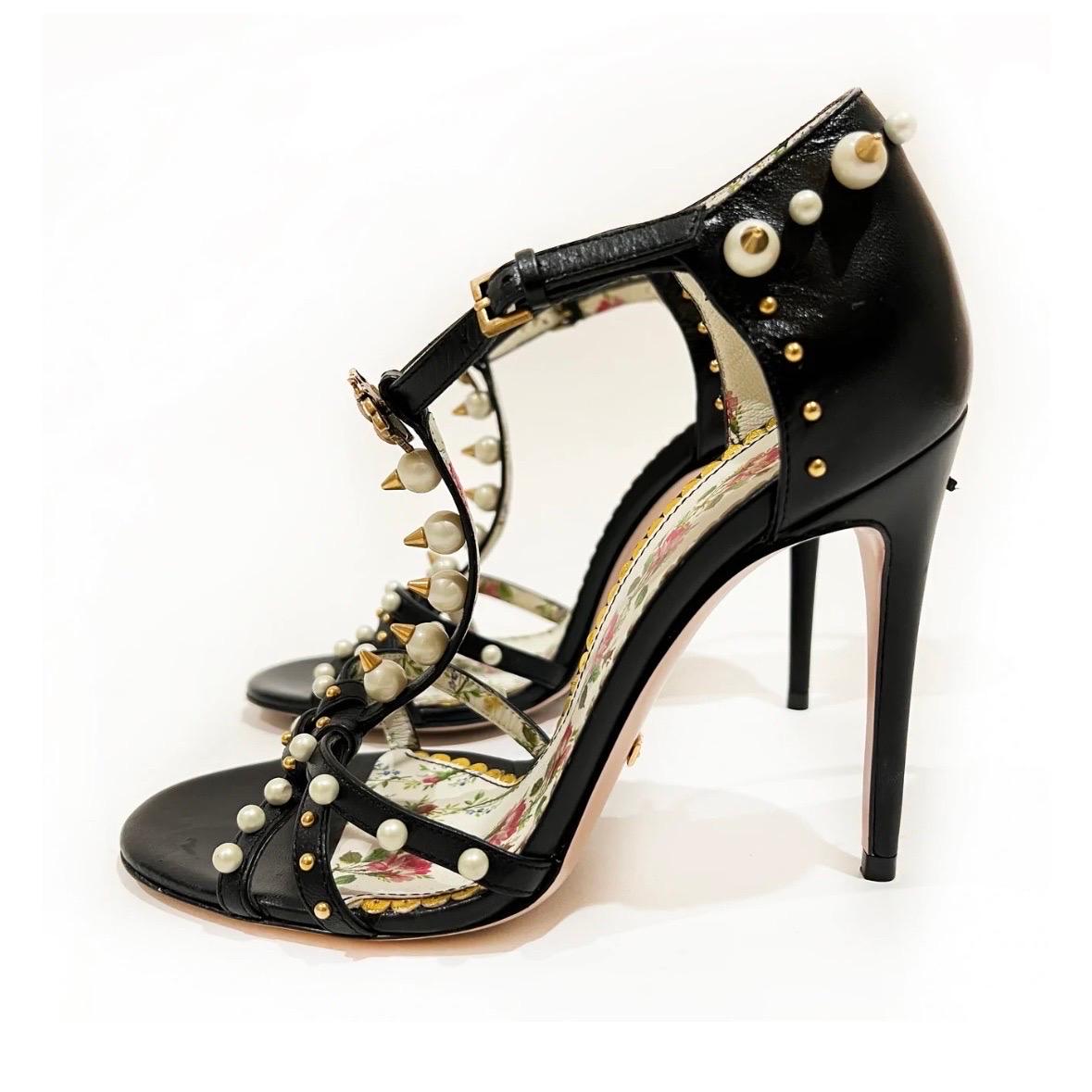 Pearl stud sandal heels by Gucci  
Made in Italy 
Black leather straps
Pearl and gold metal stud embellishments
Gucci Bee charm at ankle 
Stiletto heel  
Floral insole 
Good condition, wear on outsoles and some scratches on heels (see photo)