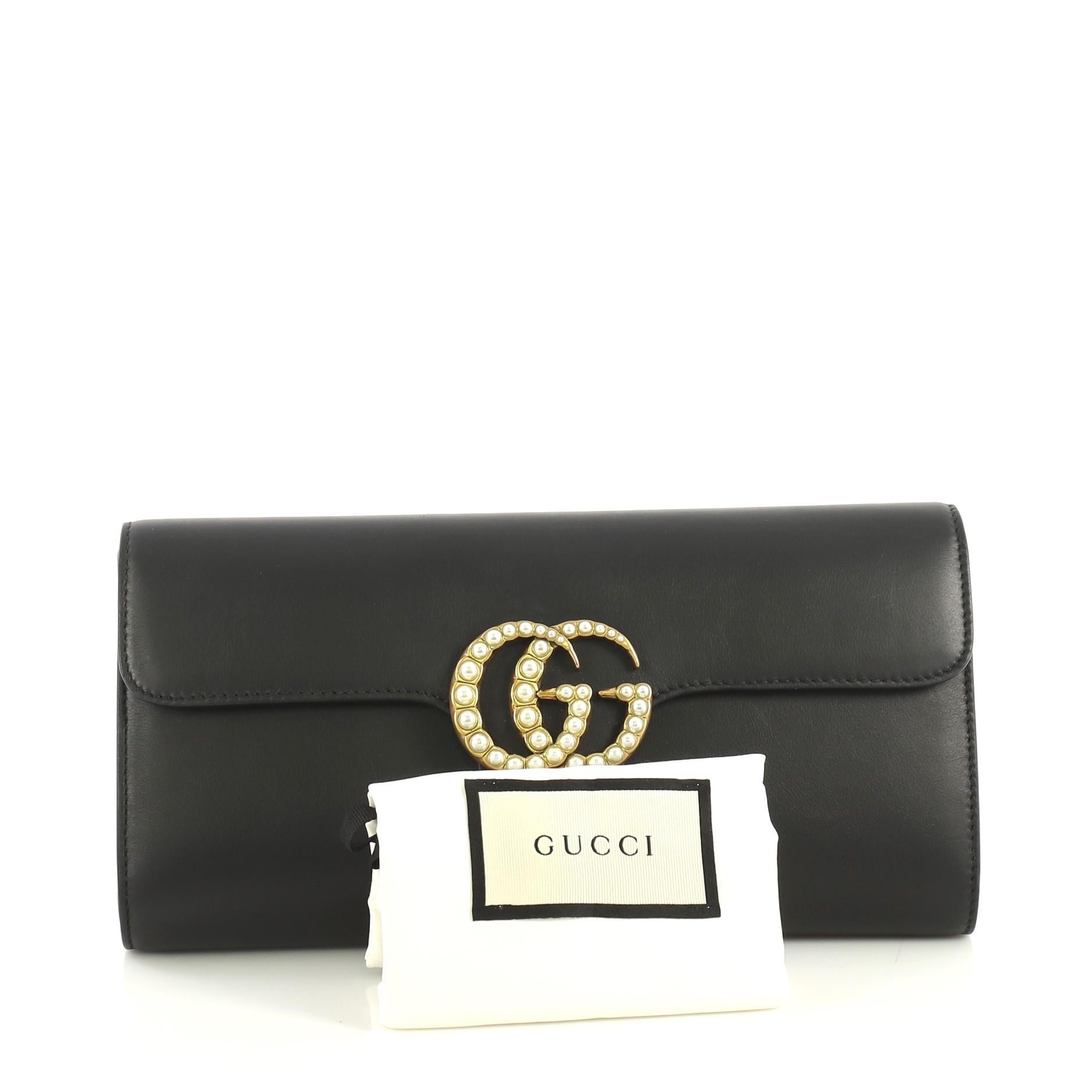 This Gucci Pearly GG Marmont Clutch Leather, crafted from black leather, features pearl studded GG logo and aged gold-tone hardware. Its magnetic closure opens to a brown leather interior with slip pocket. 

Estimated Retail Price: $1,100
Condition: