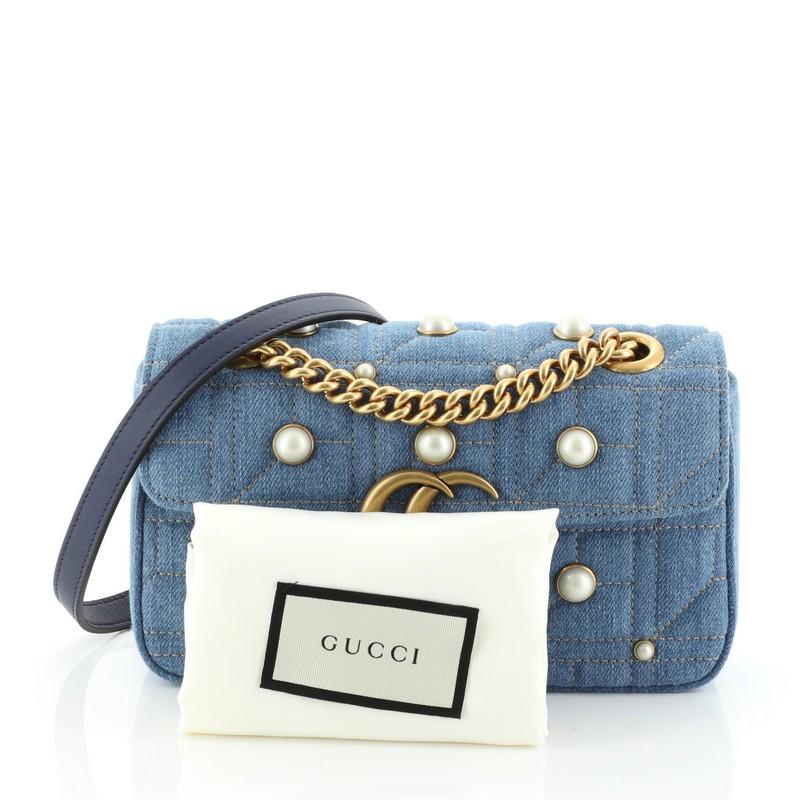 This Gucci Pearly GG Marmont Flap Bag Embellished Matelasse Denim Mini, crafted from blue matelass̩e denim, features a sliding chain strap with leather pad, flap top with interlocking GG logo, metal and pearl studs and gold-tone hardware. Its spring