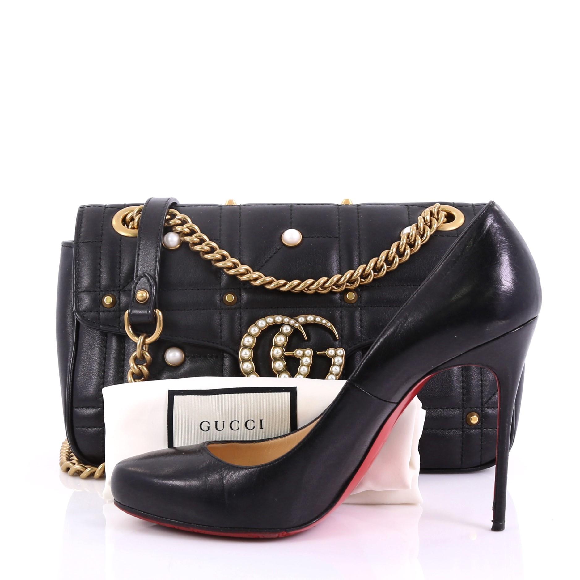 This Gucci Pearly GG Marmont Flap Bag Embellished Matelasse Leather Small, crafted from black embellished matelass̩e leather, features sliding chain strap with leather pad, flap top with interlocking GG logo, metal and pearl studs embellishment, and