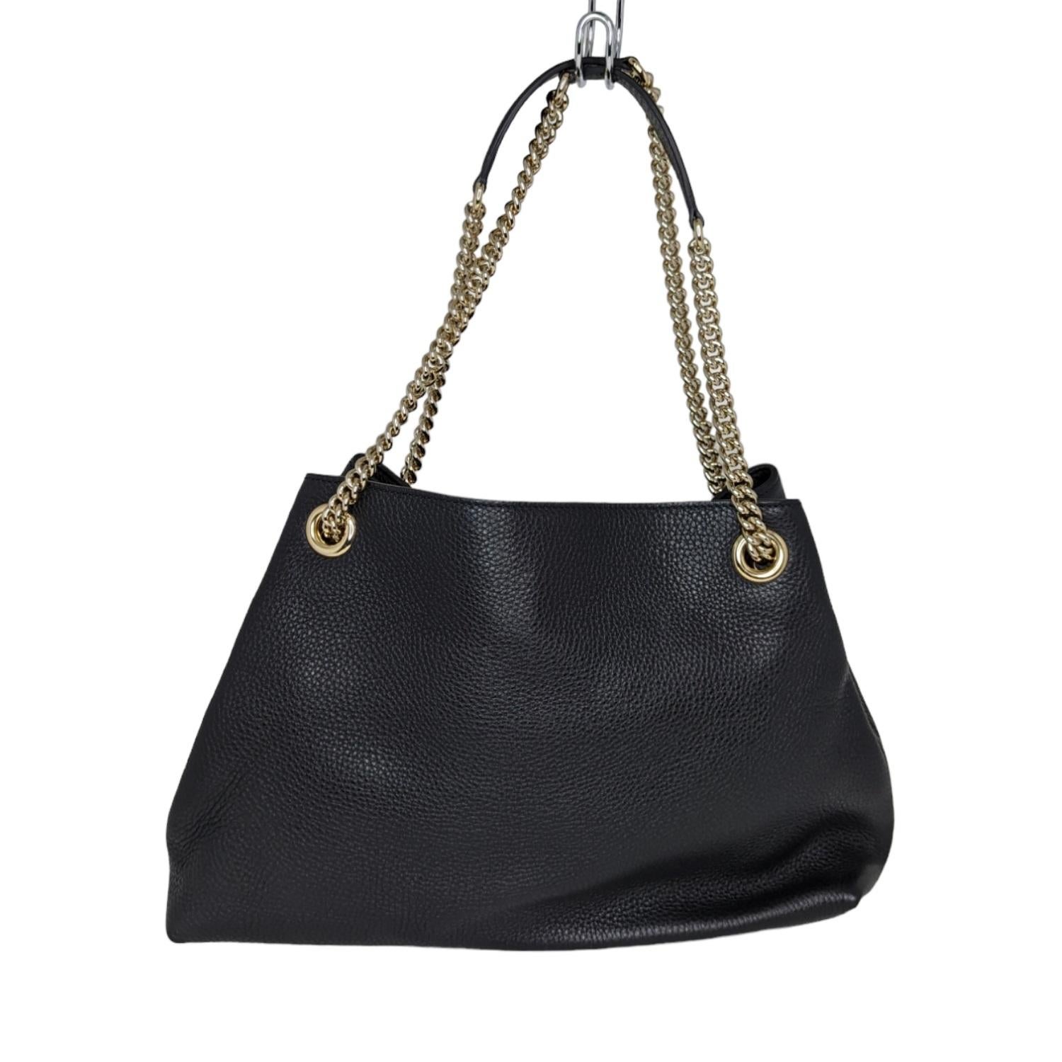 This shoulder bag is crafted of textured calfskin leather in black. The bag features a prominent front interlocking GG quilted logo, polished light gold chain link shoulder straps with shoulder pads, and a decorative light gold knobbed tassel. The