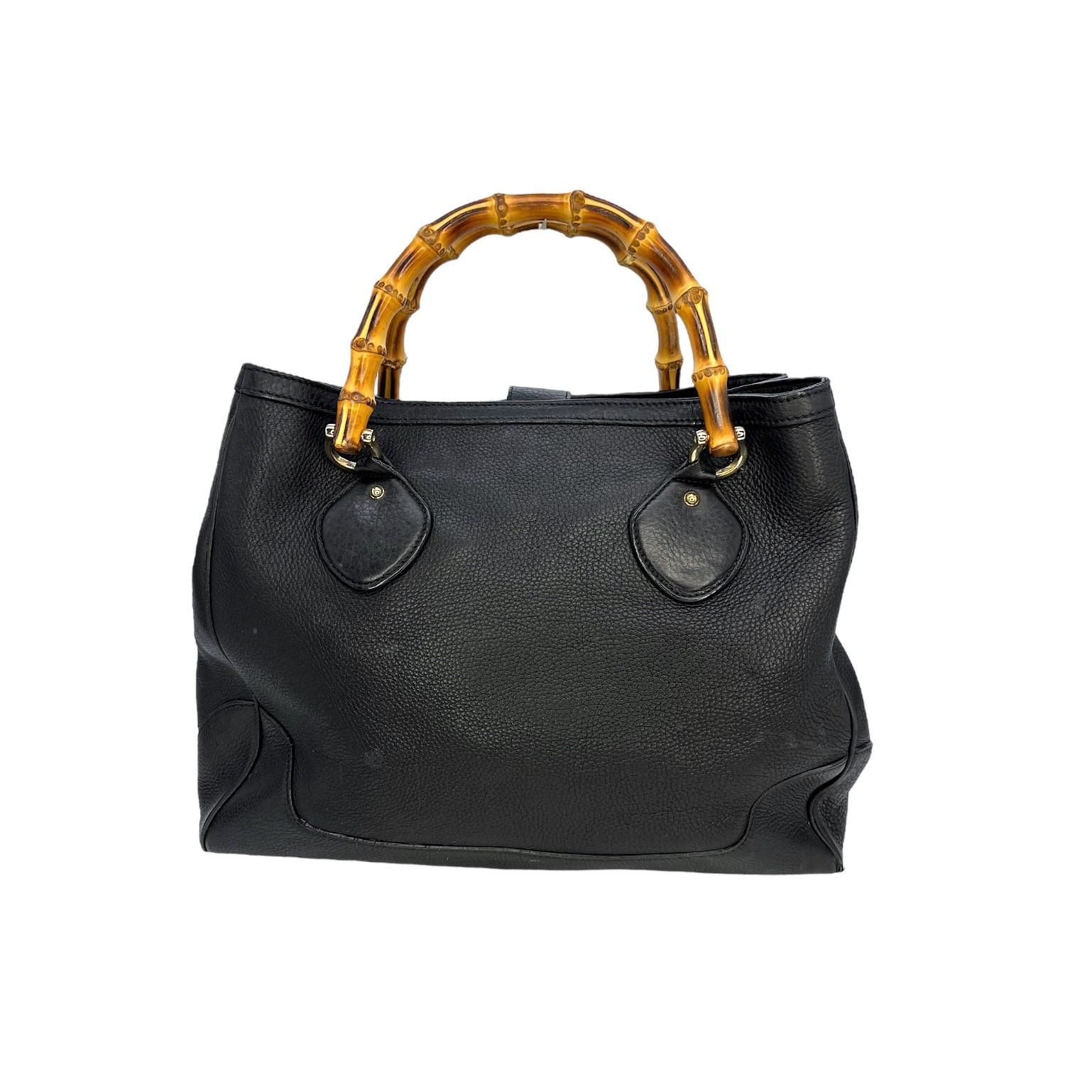 This Gucci Pebbled Leather Bamboo Diana Tote was made in Italy and it is finely crafted of a black pebbled leather exterior with gold-tone hardware features. It has round bamboo top handles. It has a magnetic snap closure and it opens up to a very